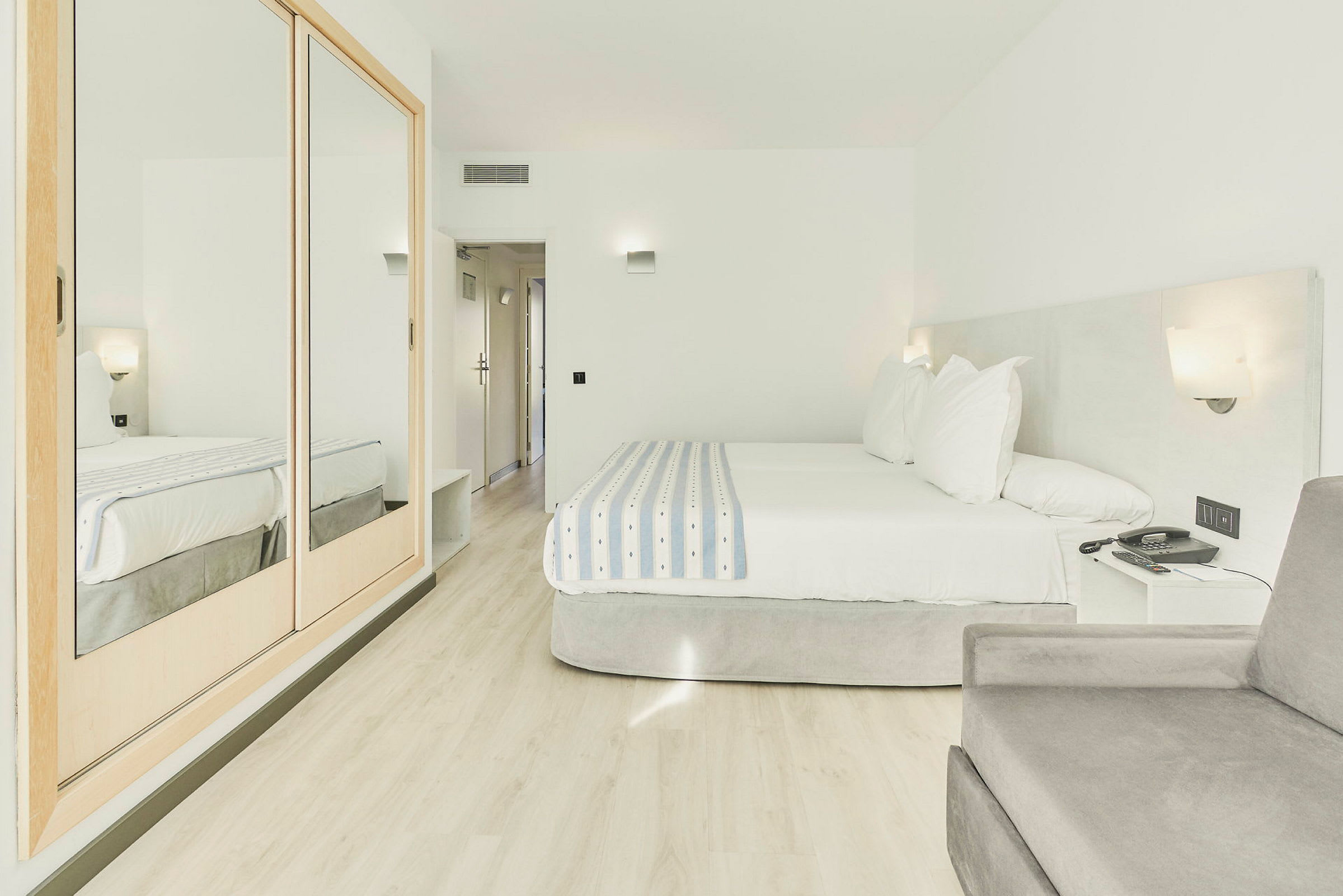 Hotellihuone, jossa on parisänky ja vaaleat kalusteet. (Tekoälyn luoma teksti)