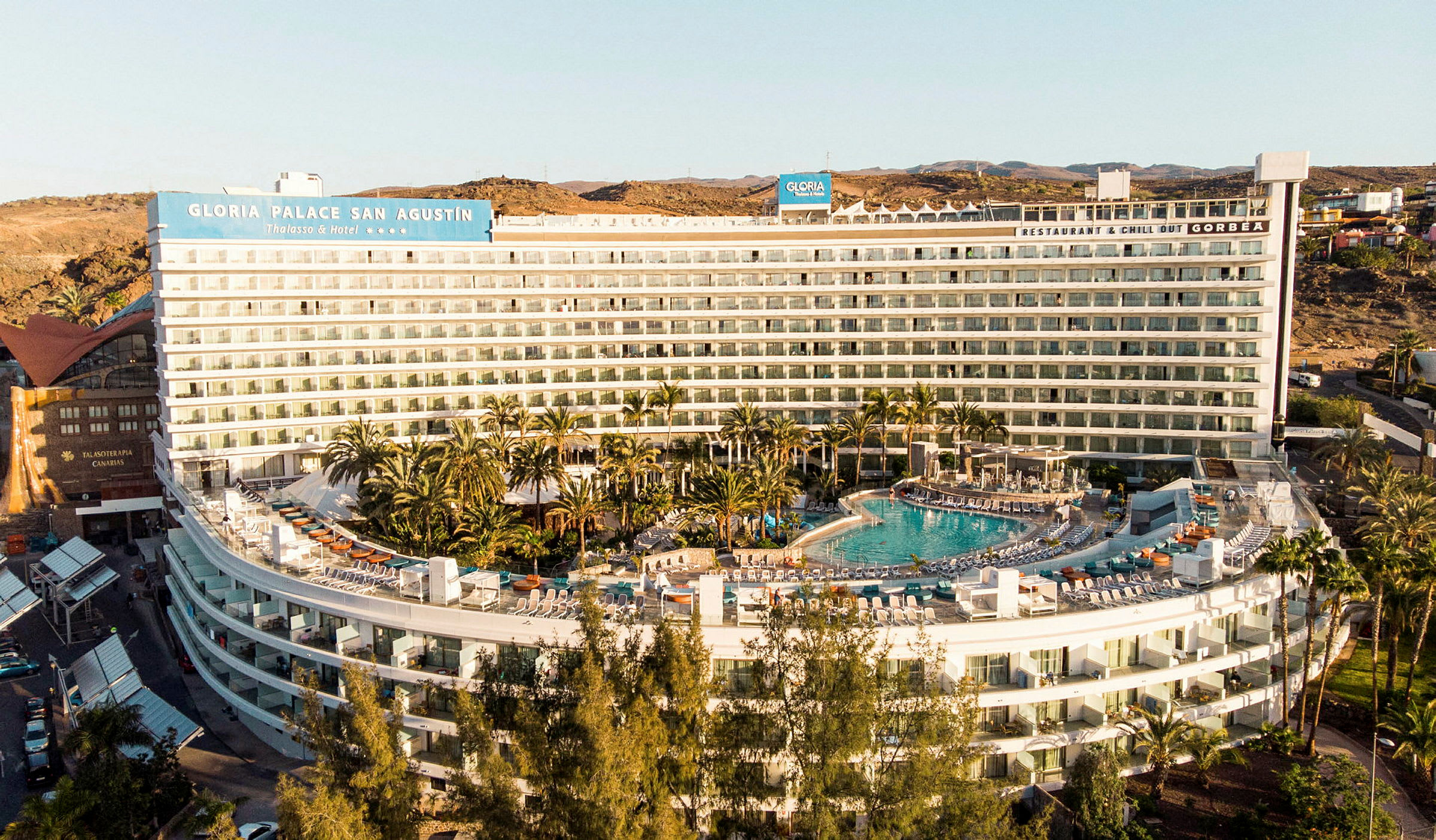 Hotellirakennus, jossa uima-allas ja ympäröivää vehreyttä. (Tekoälyn luoma teksti)