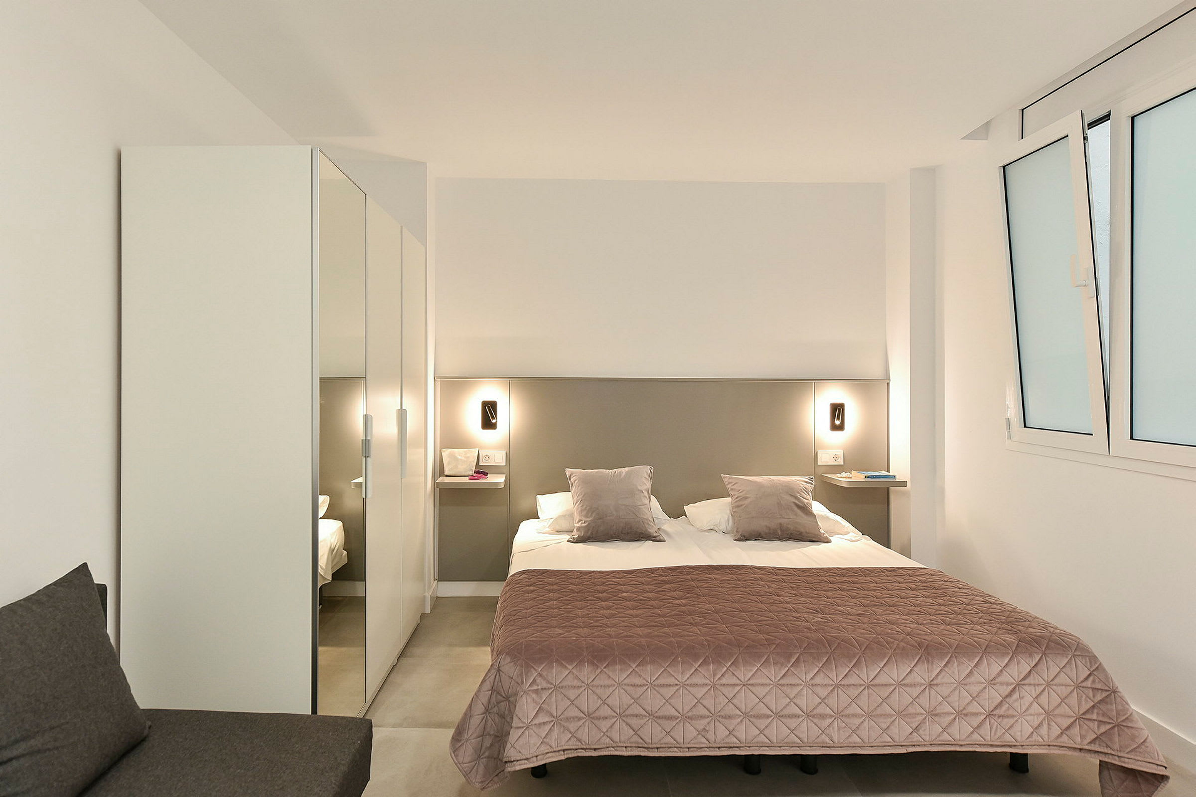 Hotellihuone, jossa parivuode, vaaleanpunainen päiväpeite ja vaatekaappi. (Tekoälyn luoma teksti)