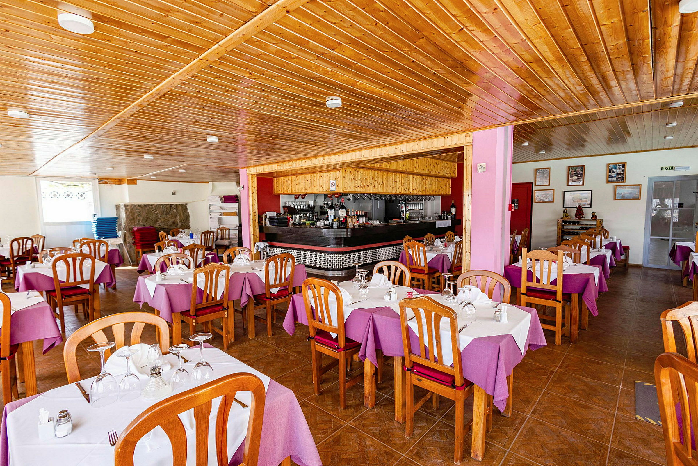 Ravintola, jossa on puusisustus, violetit pöytäliinat ja puiset tuolit. (Tekoälyn luoma teksti)