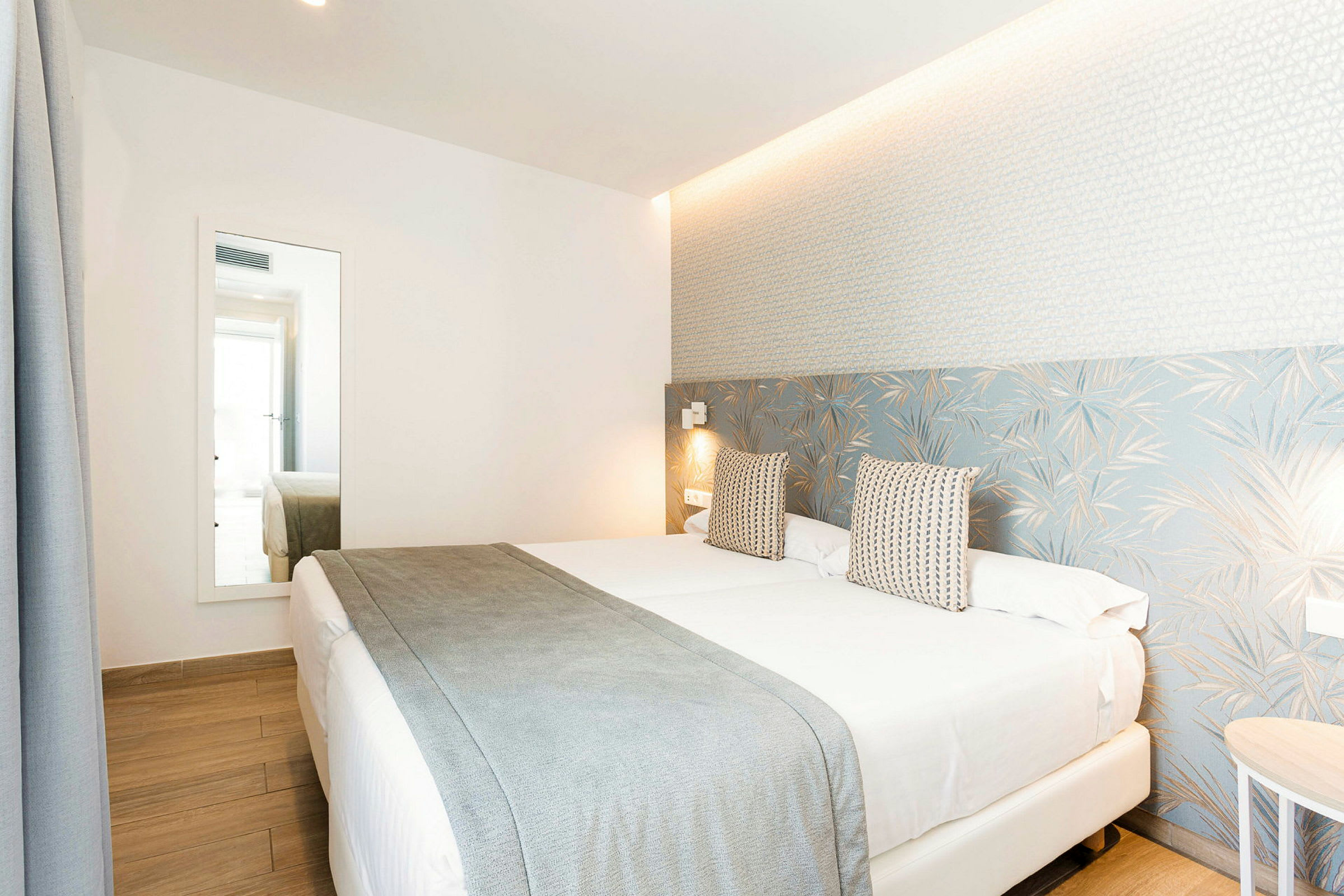 Hotellihuone, jossa on parivuode, vaalea sisustus ja suuri peili. (Tekoälyn luoma teksti)