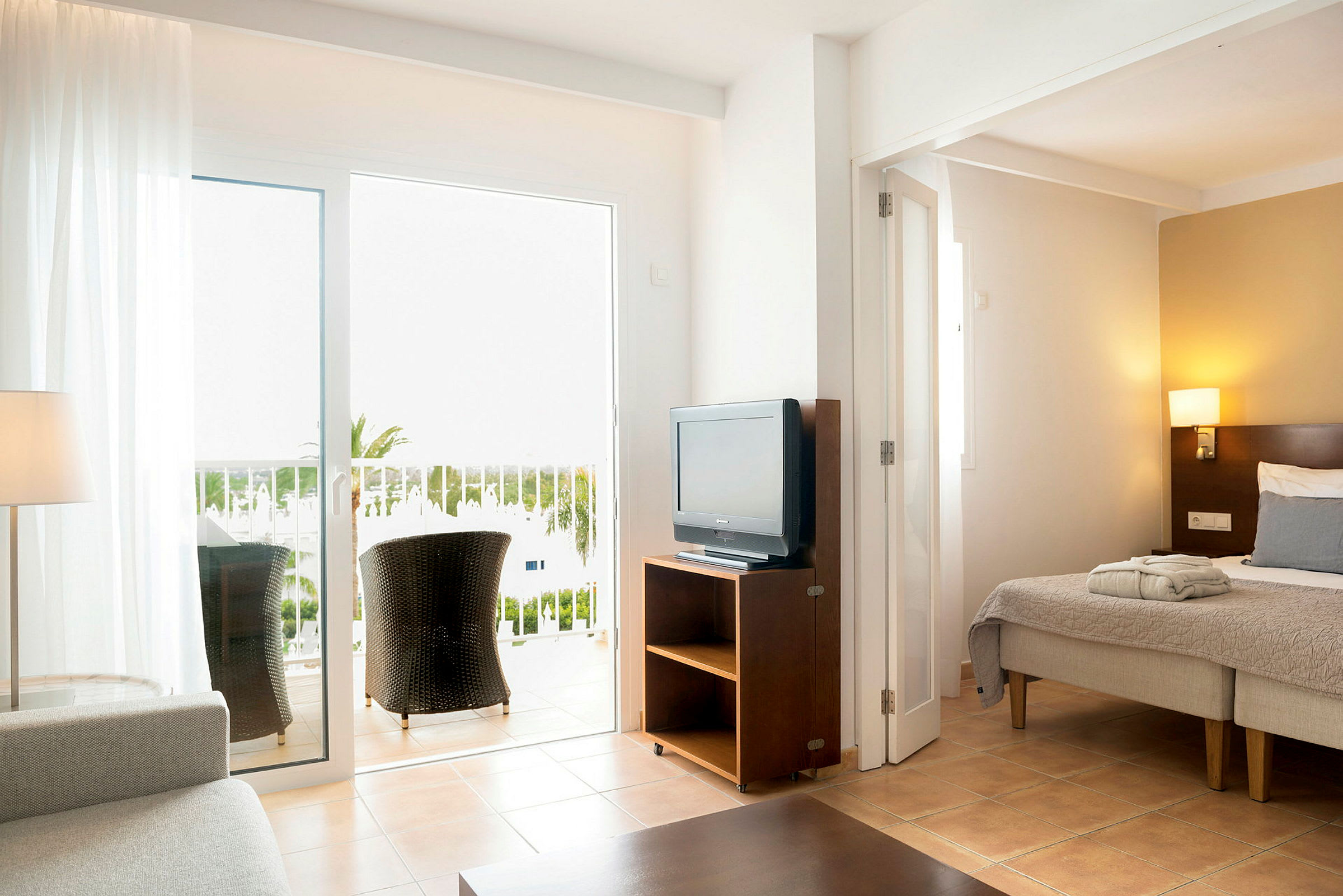 Hotellihuone, jossa sänky, televisio ja parveke istuinpaikoilla. (Tekoälyn luoma teksti)