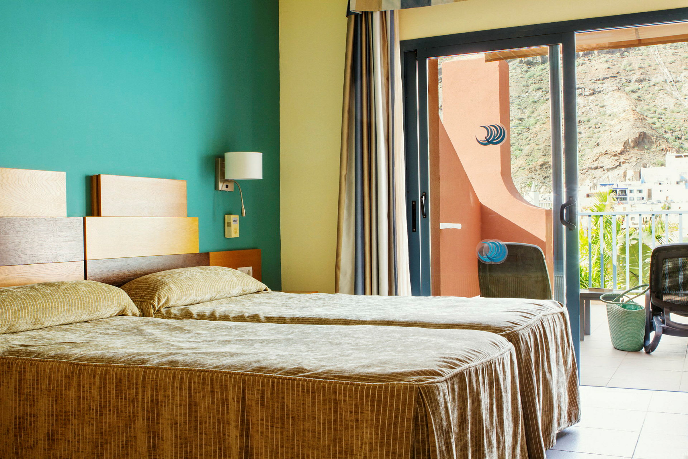 Hotellihuone, jossa kaksi erillistä vuodetta ja parveke näkymällä. (Tekoälyn luoma teksti)