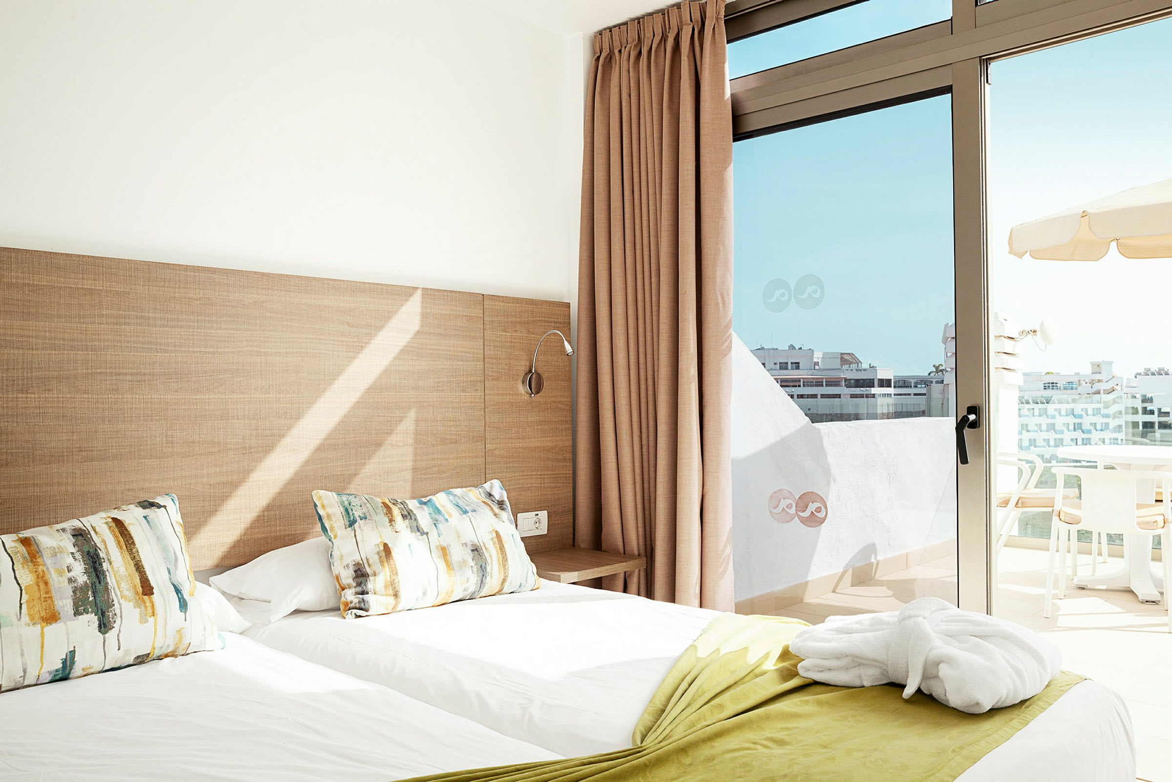 Hotellihuone, jossa kaksi erillistä sänkyä ja parveke näkymällä. (Tekoälyn luoma teksti)
