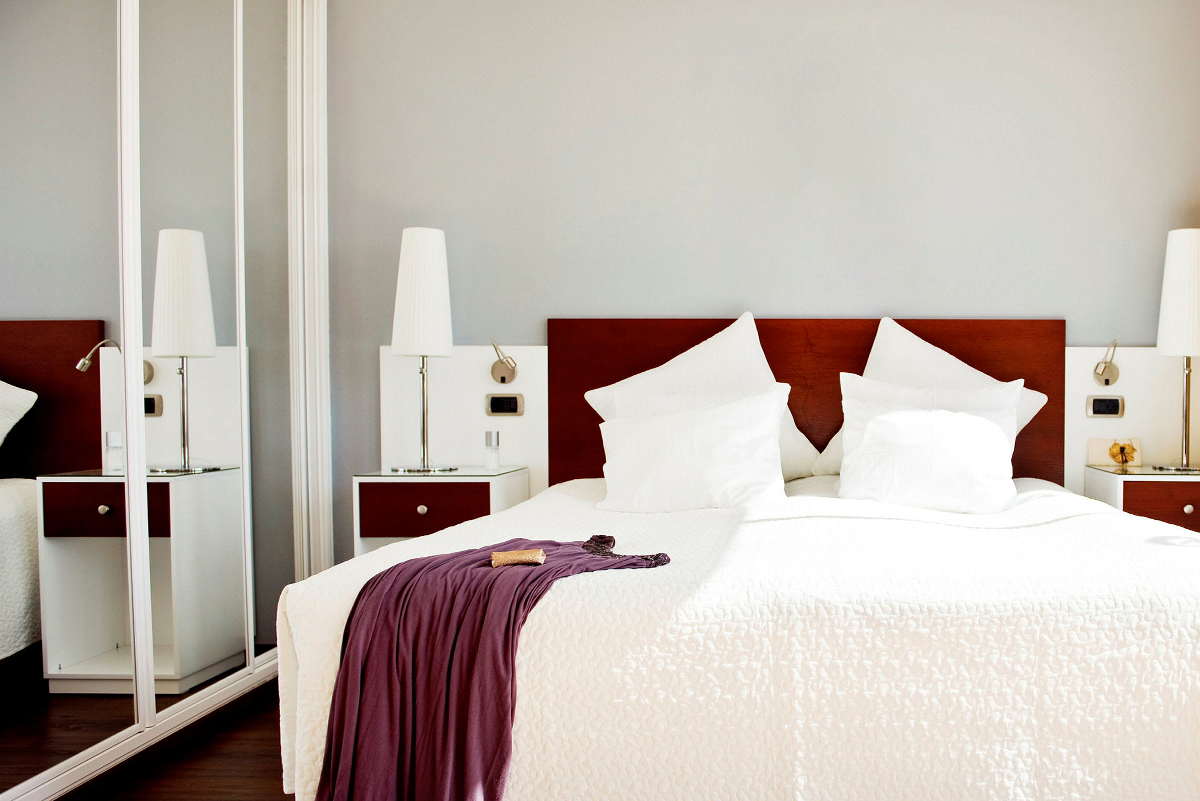 Hotellihuone, jossa on parivuode, valkoiset vuodevaatteet ja tyynyt sekä peitto verhottuna huovalla. (Tekoälyn luoma teksti)