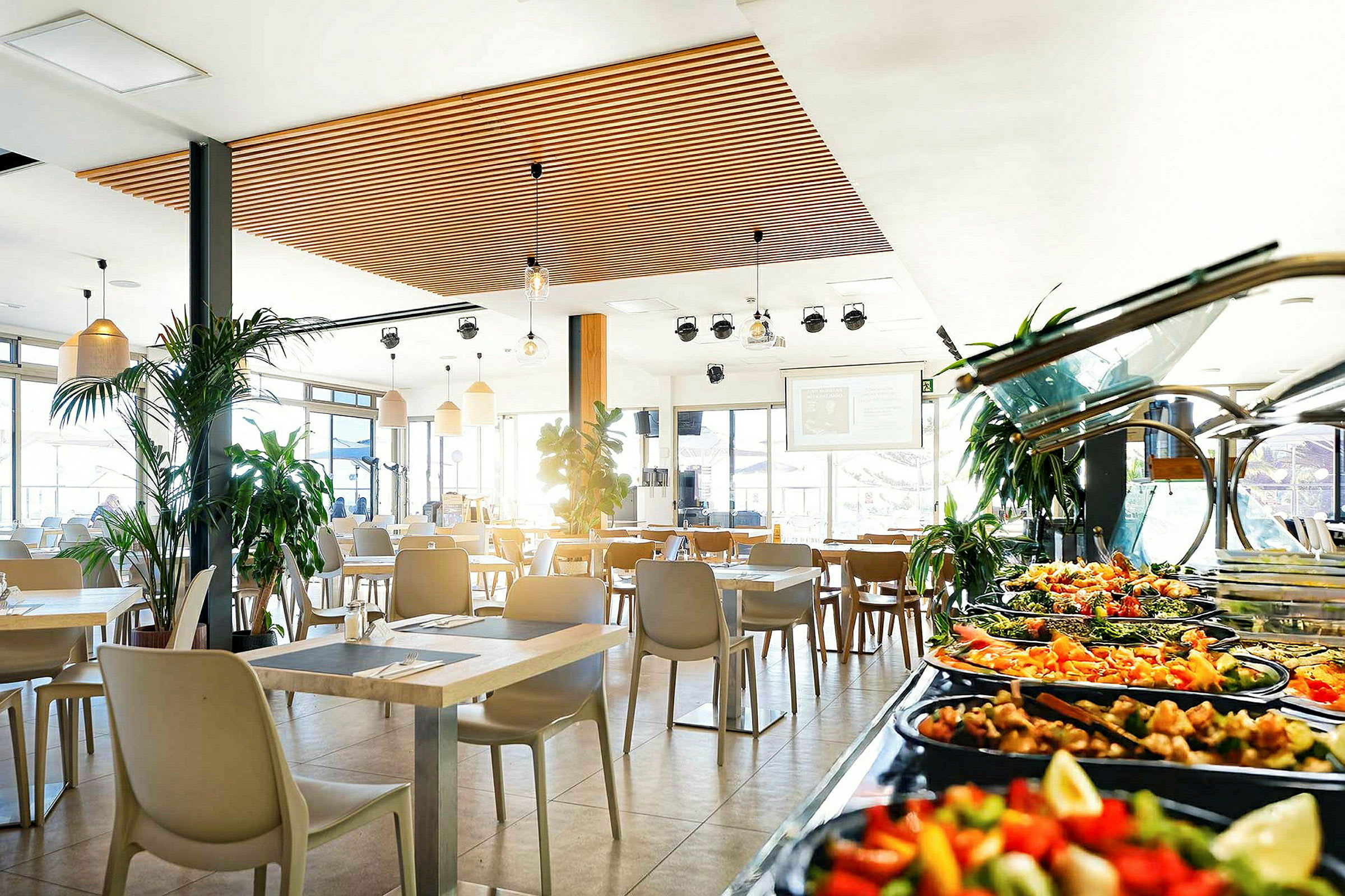 Ravintola, jossa modernit kalusteet ja buffetpöytä salaatteineen ja lisukkeineen. (Tekoälyn luoma teksti)
