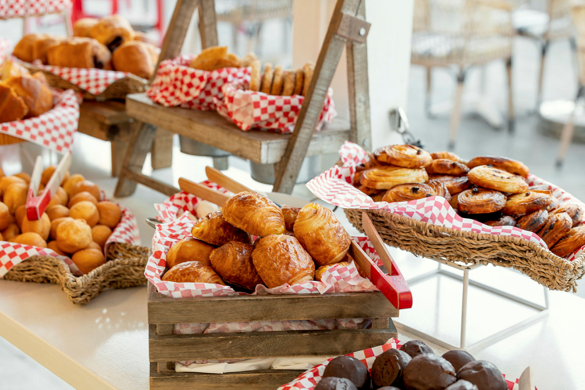 Näyttely erilaisista leivonnaisista, mukaan lukien croissantit, pullat ja tanskalaiset viinerit, koreissa ja puulaatikoissa. (Tekoälyn luoma teksti)