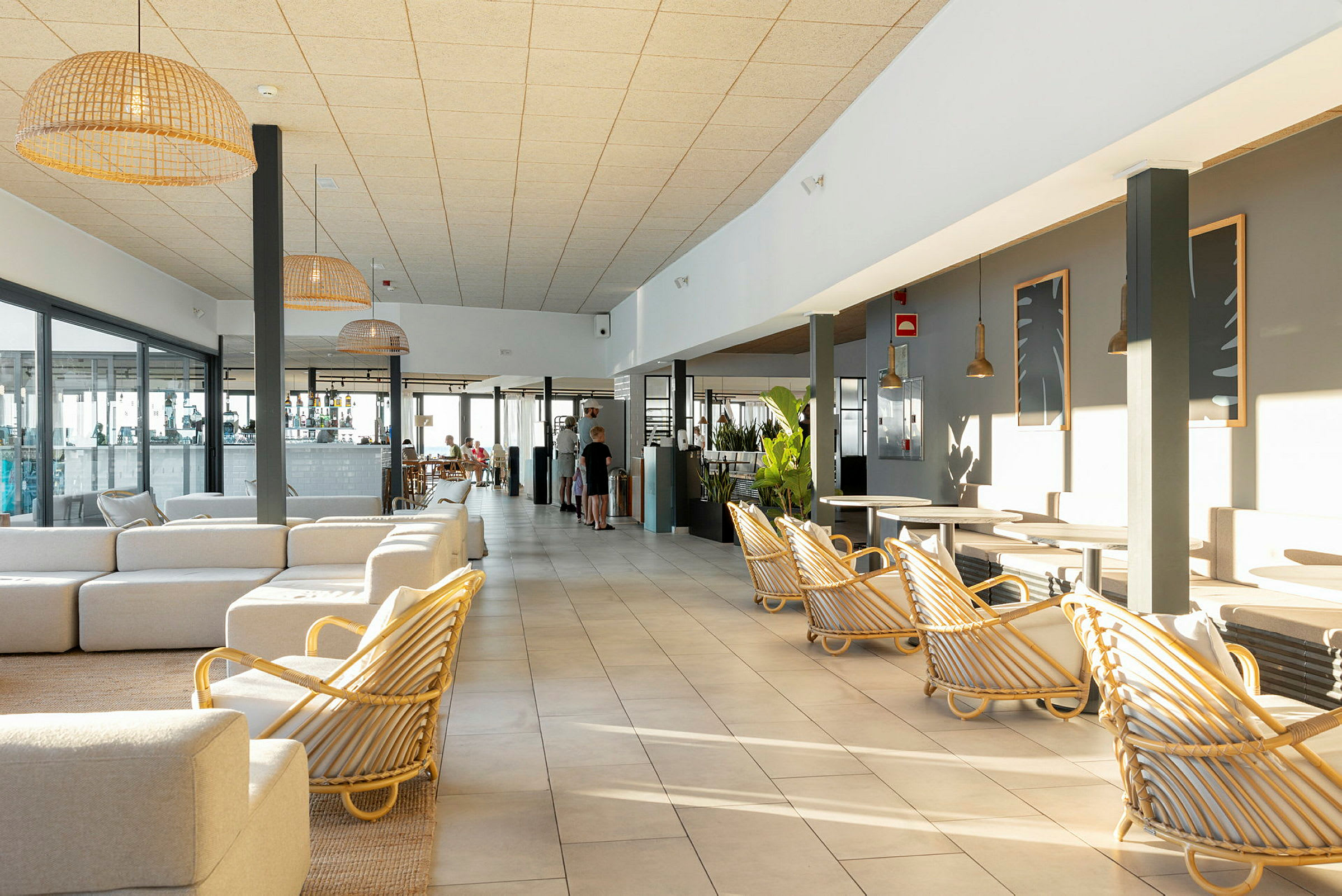 Aurinkoinen hotellihuone, jossa on vaaleat huonekalut ja suuret ikkunat. (Tekoälyn luoma teksti)
