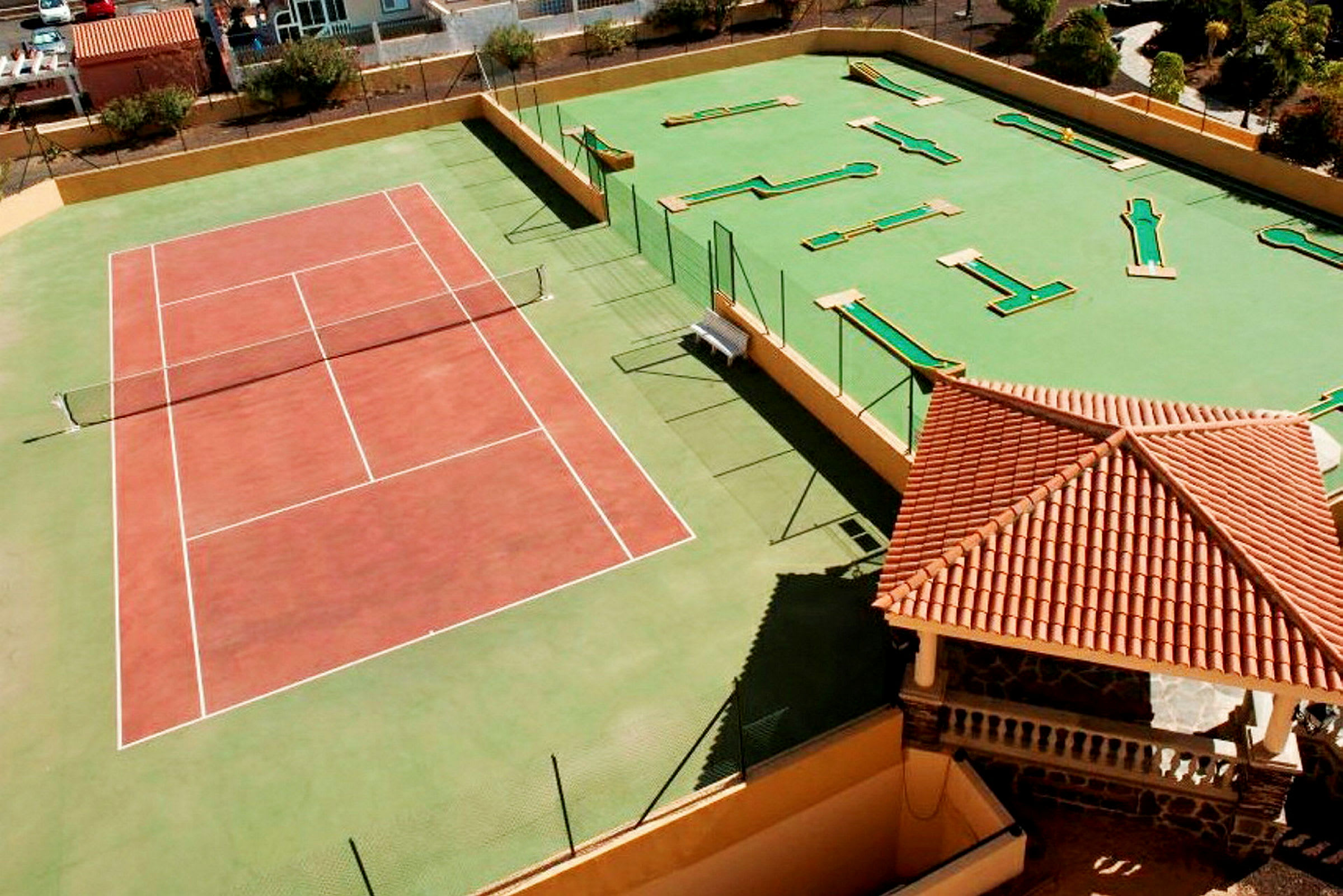 Tenniskenttä ja minigolfalue punakattoisen rakennuksen vieressä. (Tekoälyn luoma teksti)