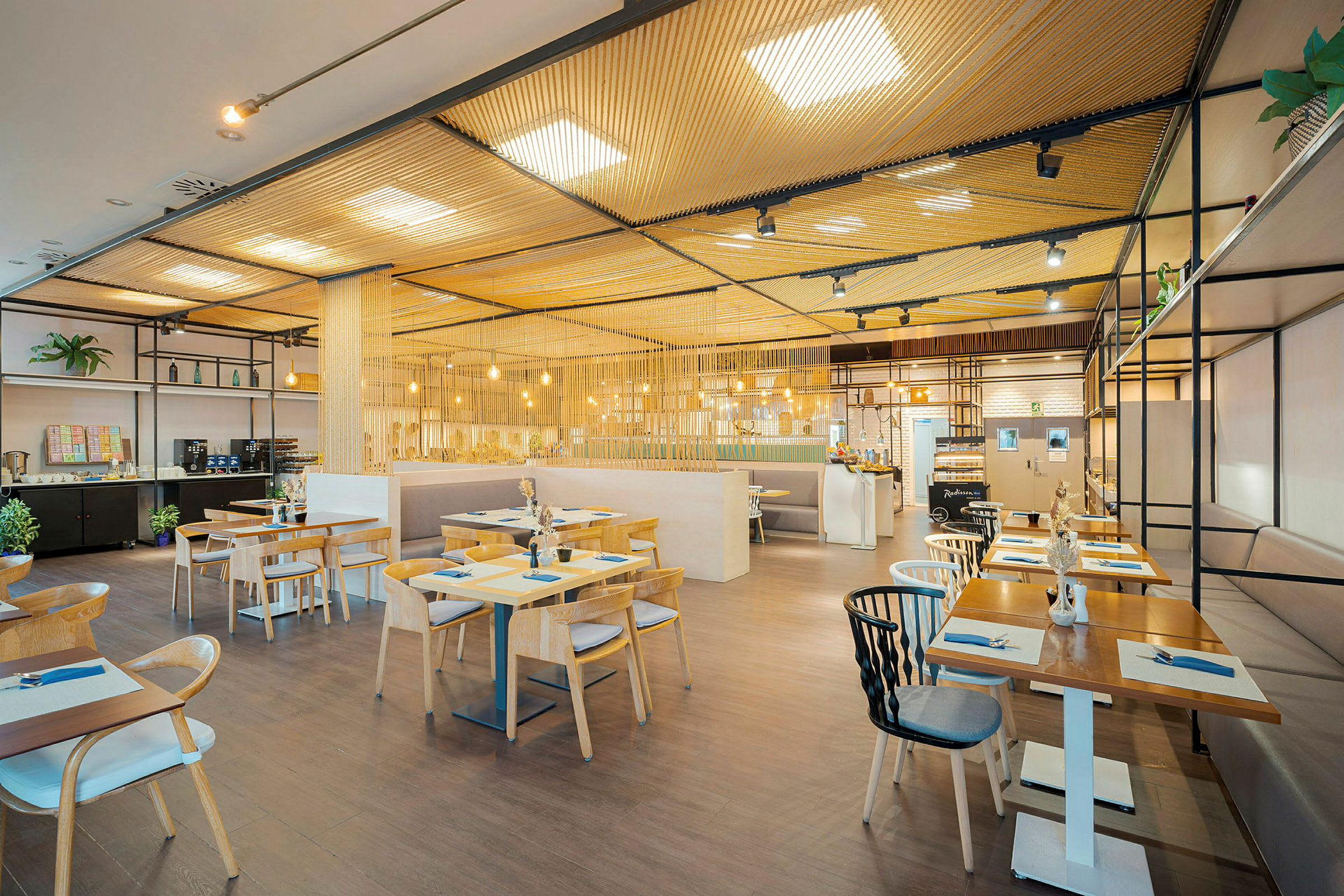 Moderni ravintola, jossa on puupöytiä ja tuoleja, valaistu riippulampuilla. (Tekoälyn luoma teksti)