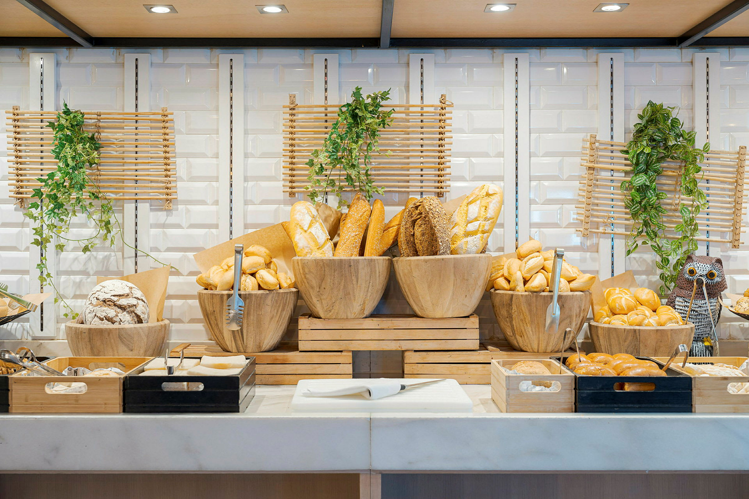 Buffet, jossa erilaisia leipiä aseteltuna puukulhoihin ja tarjottimille. (Tekoälyn luoma teksti)