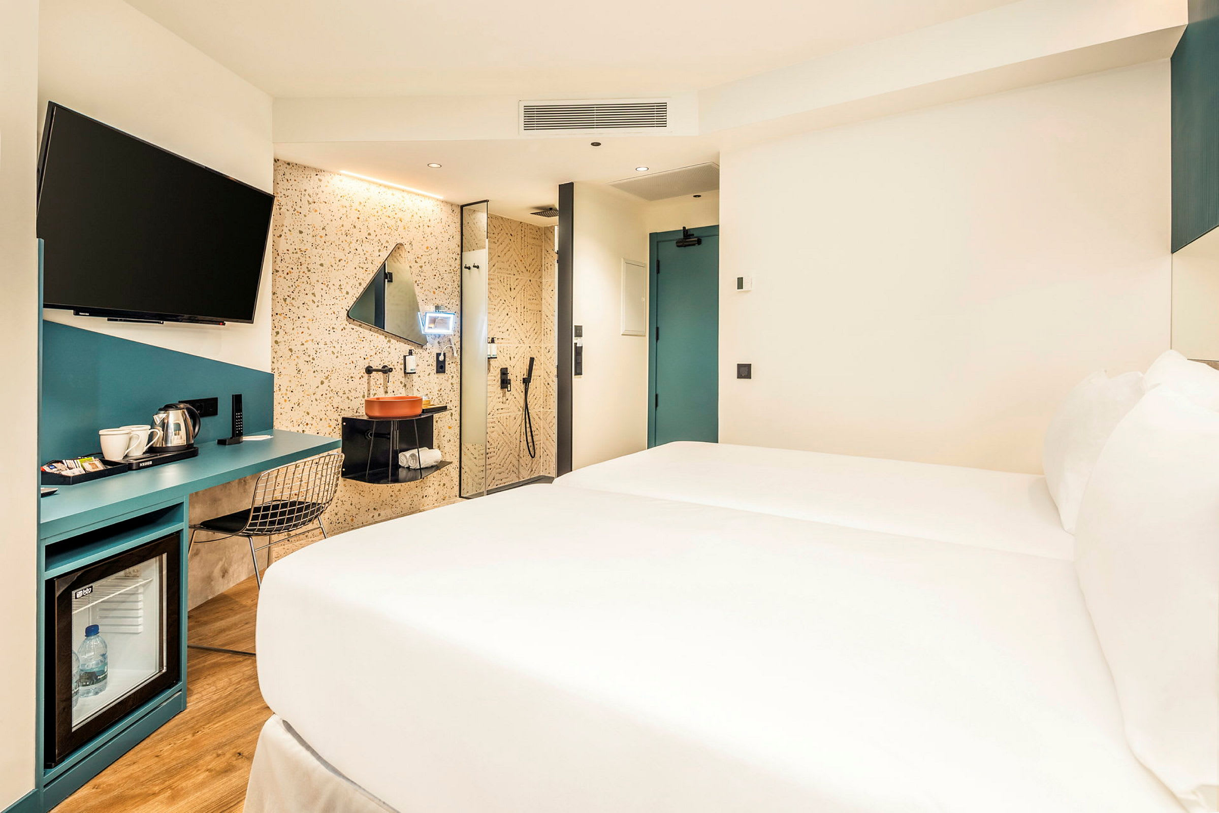 Hotellihuone, jossa sänky, työpöytä ja kylpyhuonealue. (Tekoälyn luoma teksti)