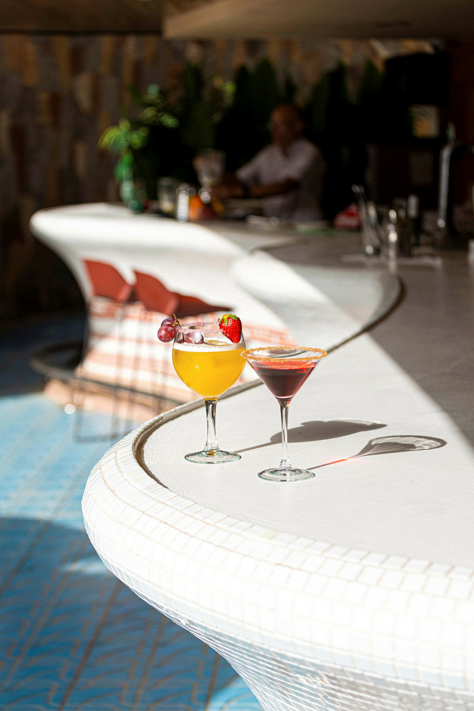 Kaksi cocktailia seisoo valkoisella baaritiskillä. (Tekoälyn luoma teksti)