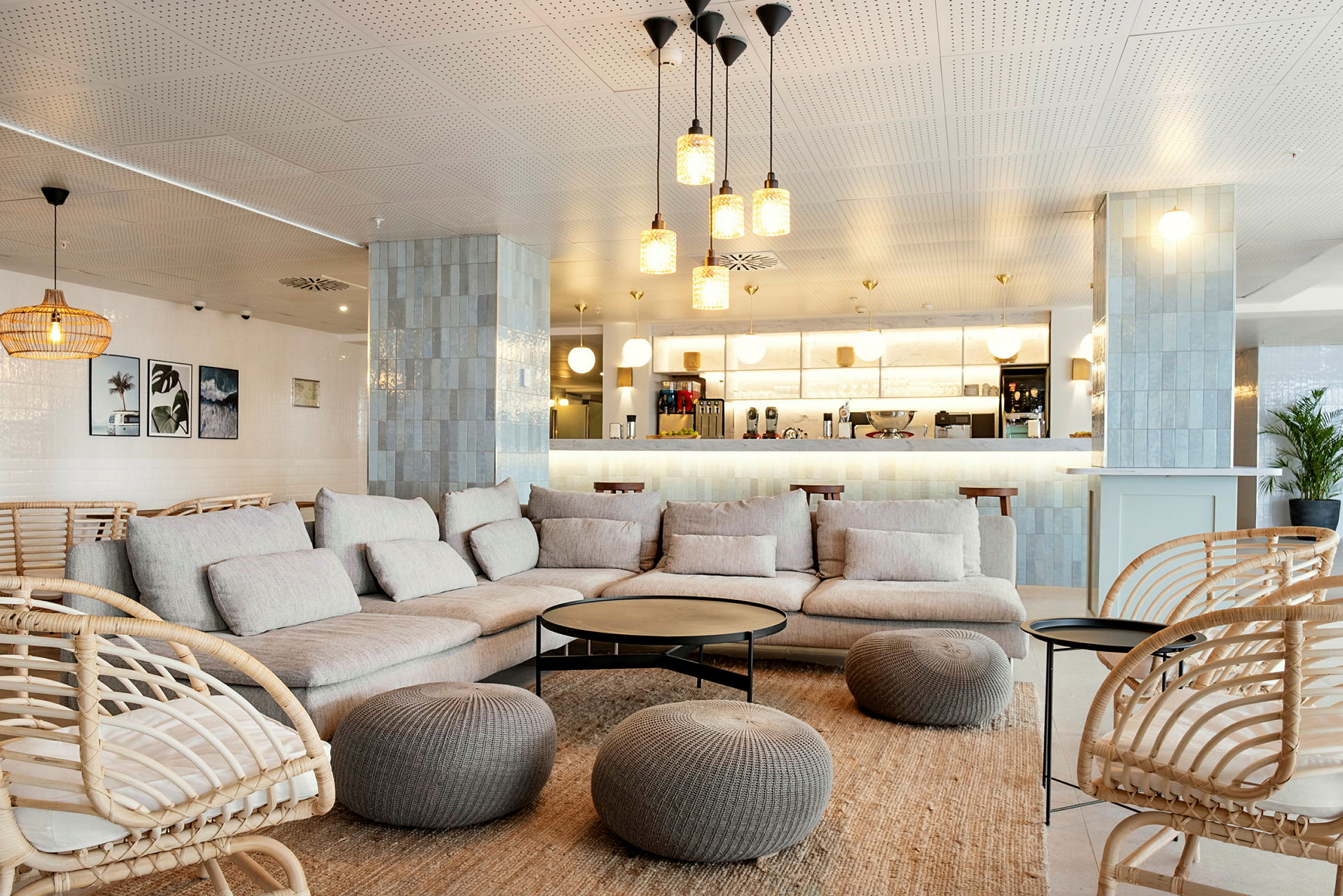 Moderni lounge, jossa beigejä sohvia ja korituoleja, sisustettu pöydillä ja koristeilla sekä taustalla kahvibaari. (Tekoälyn luoma teksti)