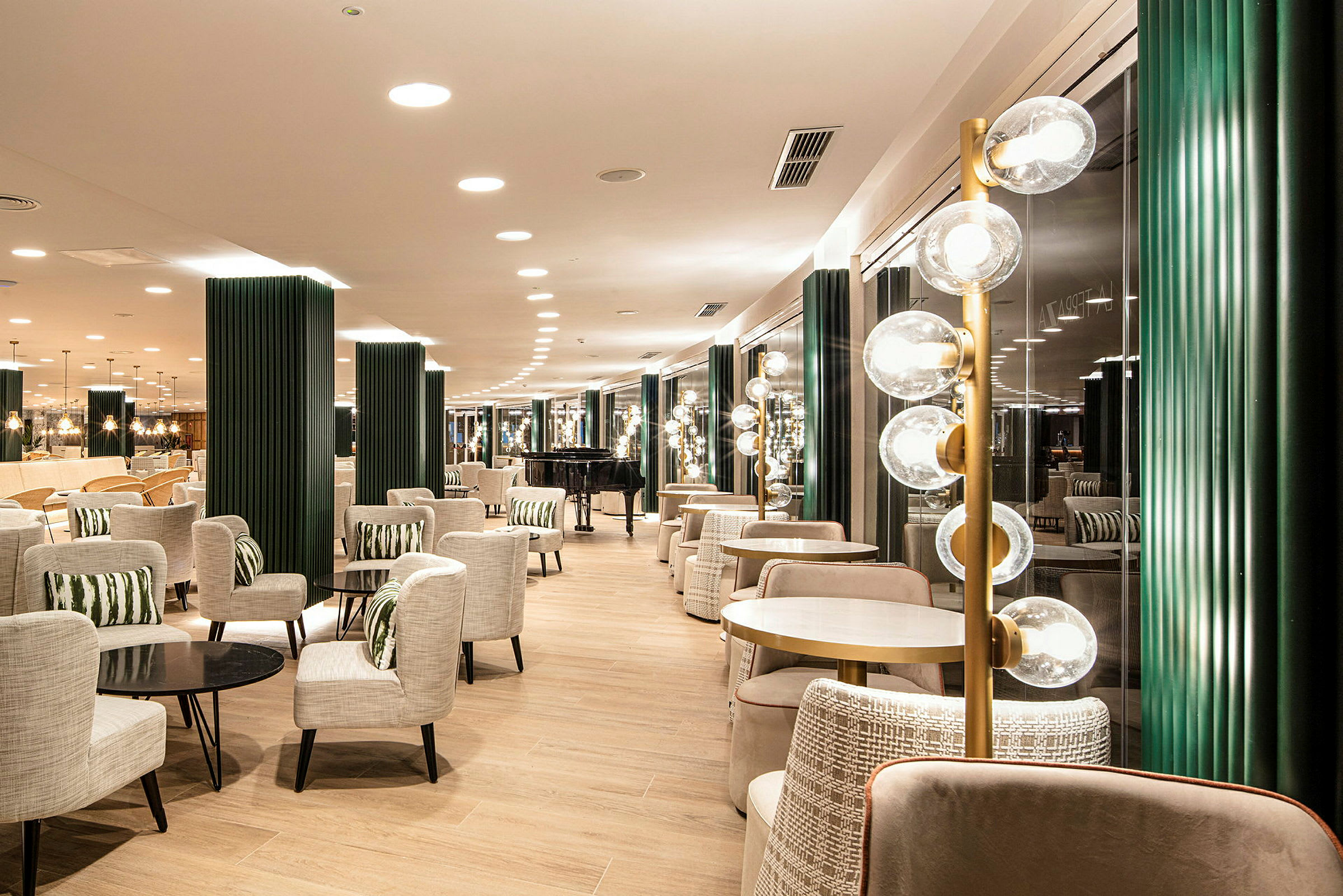 Moderni lounge-tila, jossa on pöytiä, tuoleja ja koristeellisia valaisimia. (Tekoälyn luoma teksti)