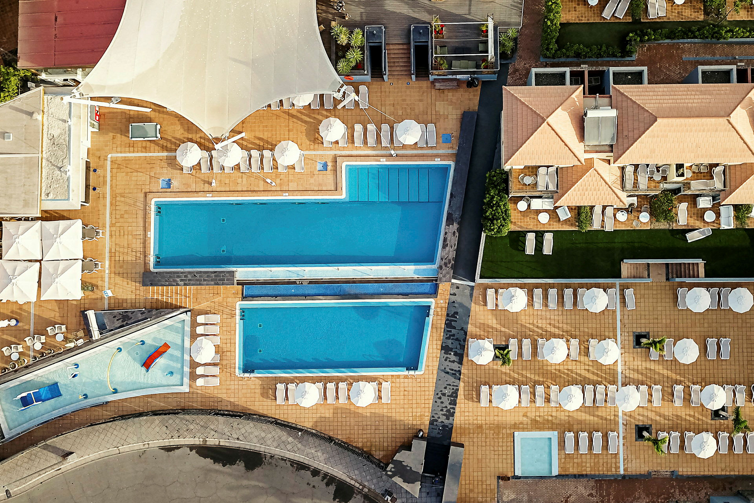 Ilmakuva hotellialueesta, jossa on uima-altaita ja aurinkotuoleja. (Tekoälyn luoma teksti)