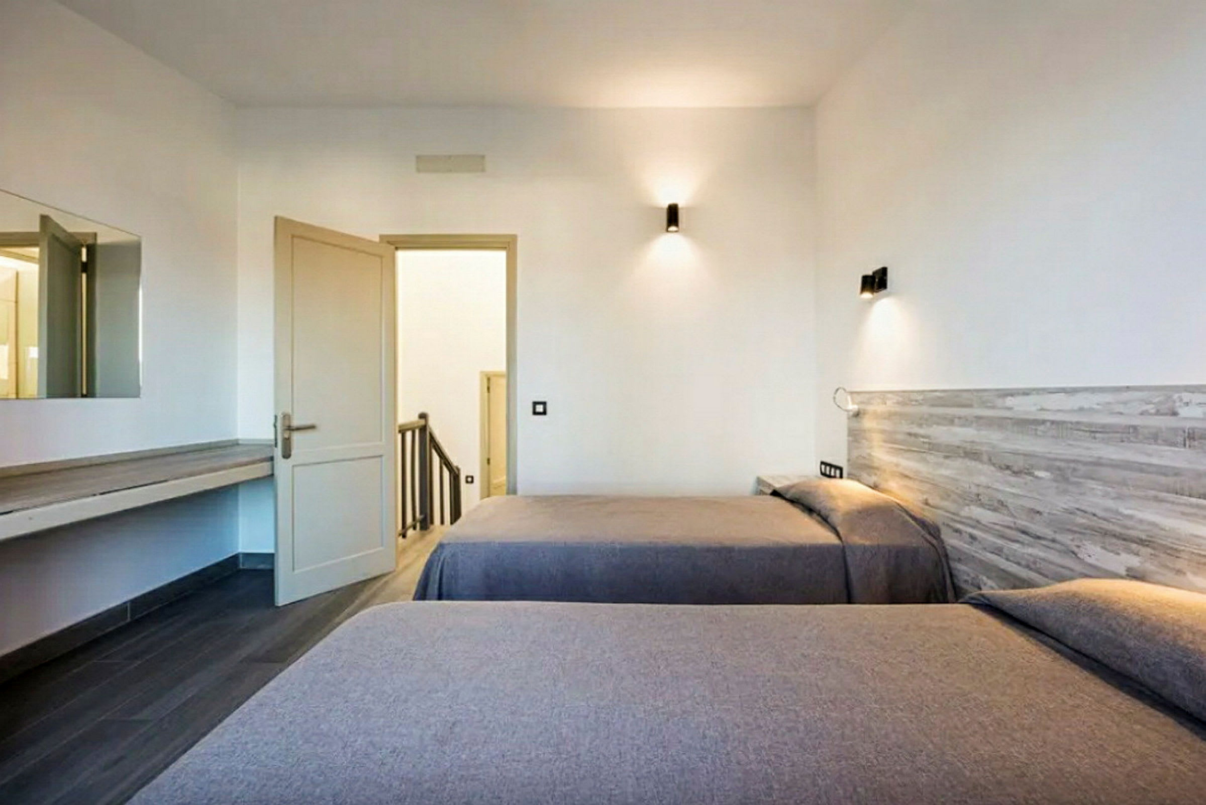 Hotellihuone, jossa kaksi erillistä vuodetta ja avoin ovi portaikkoon. (Tekoälyn luoma teksti)