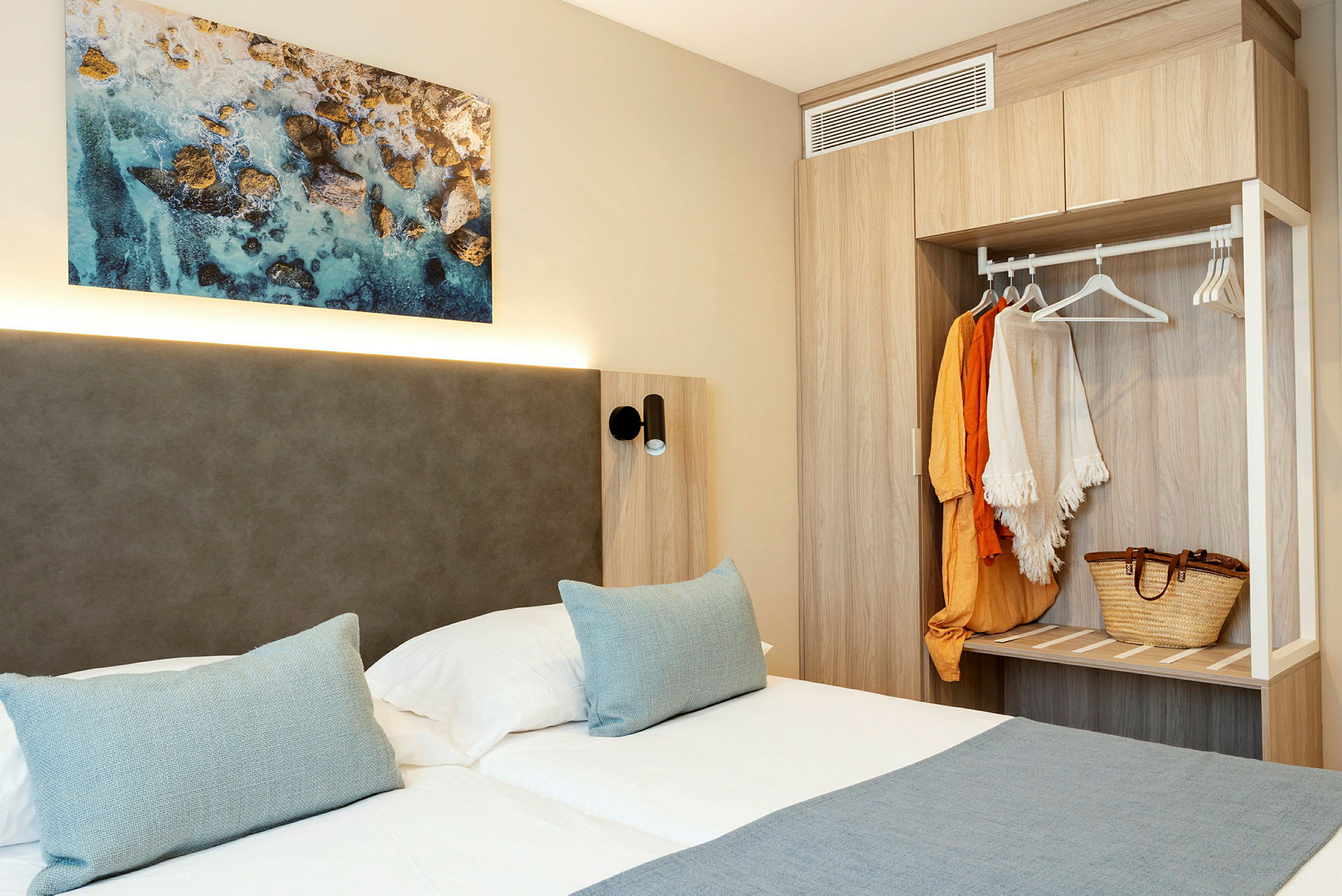 Kuva hotellihuoneesta, jossa on parivuode, seinätaidetta ja vaatekaappi. (Tekoälyn luoma teksti)