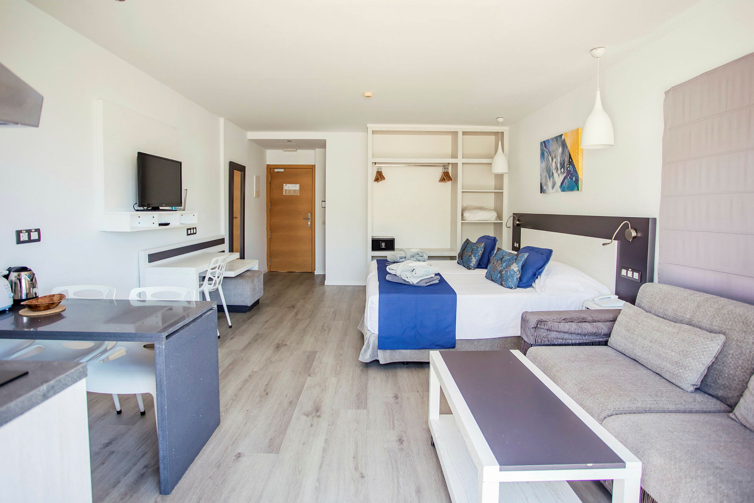 Hotellihuone, jossa on parivuode, istuma-alue ja keittiötila. (Tekoälyn luoma teksti)