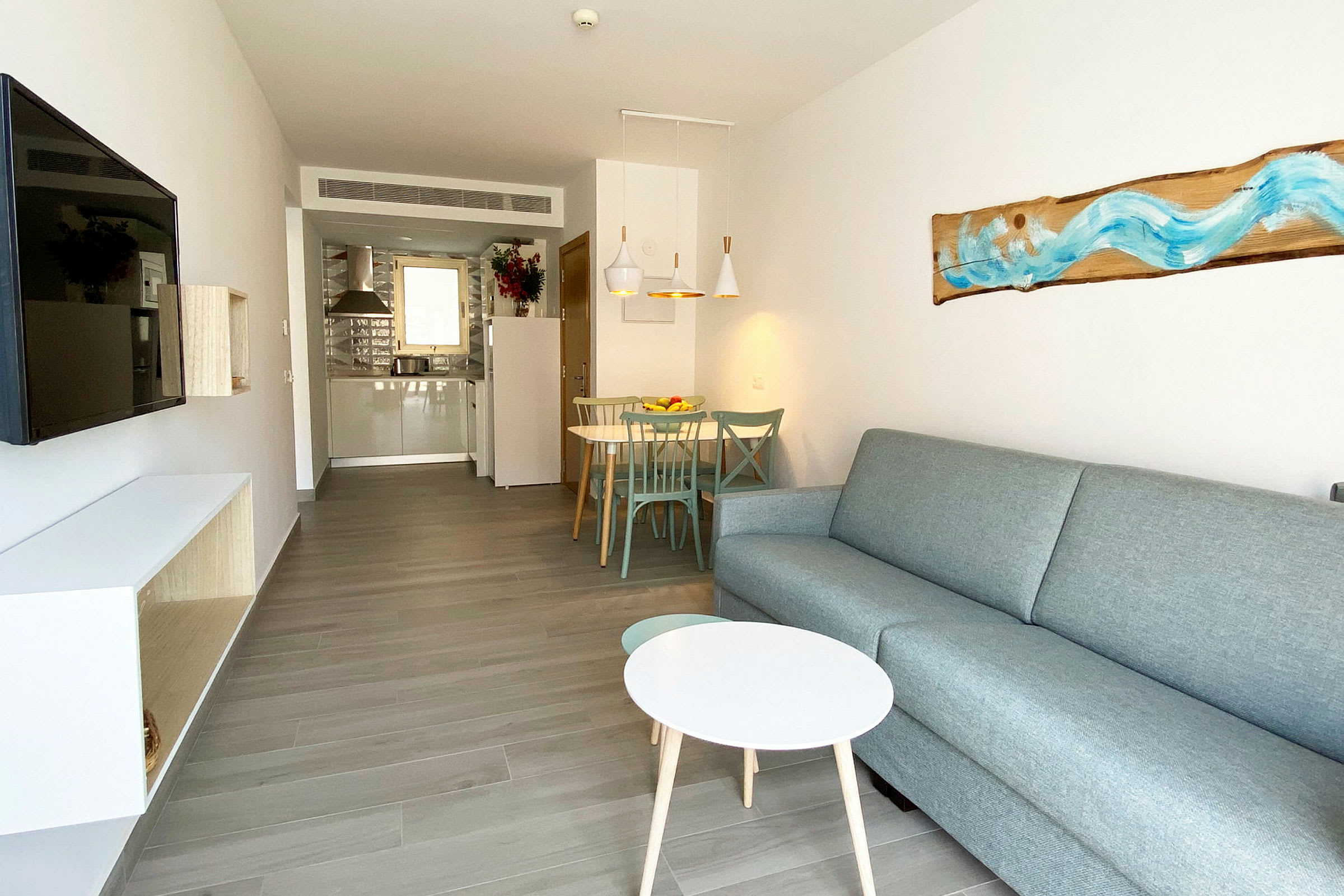 Kuva nykyaikaisesta hotellihuoneesta, jossa on sohva, sohvalipöytä, TV ja ruokailualue. (Tekoälyn luoma teksti)
