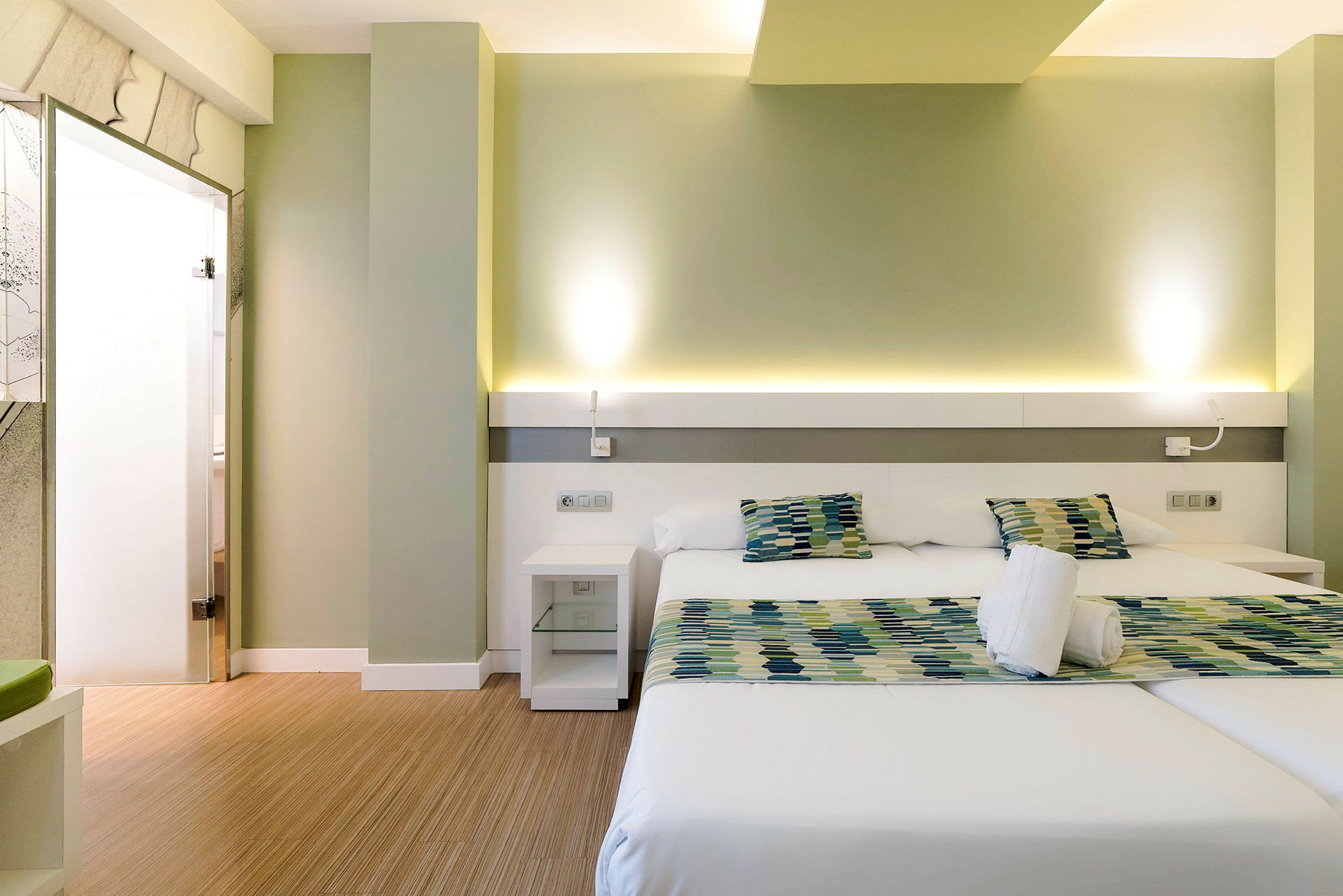 Moderni hotellihuone, jossa kaksi yhden hengen vuodetta ja istuinryhmä. (Tekoälyn luoma teksti)