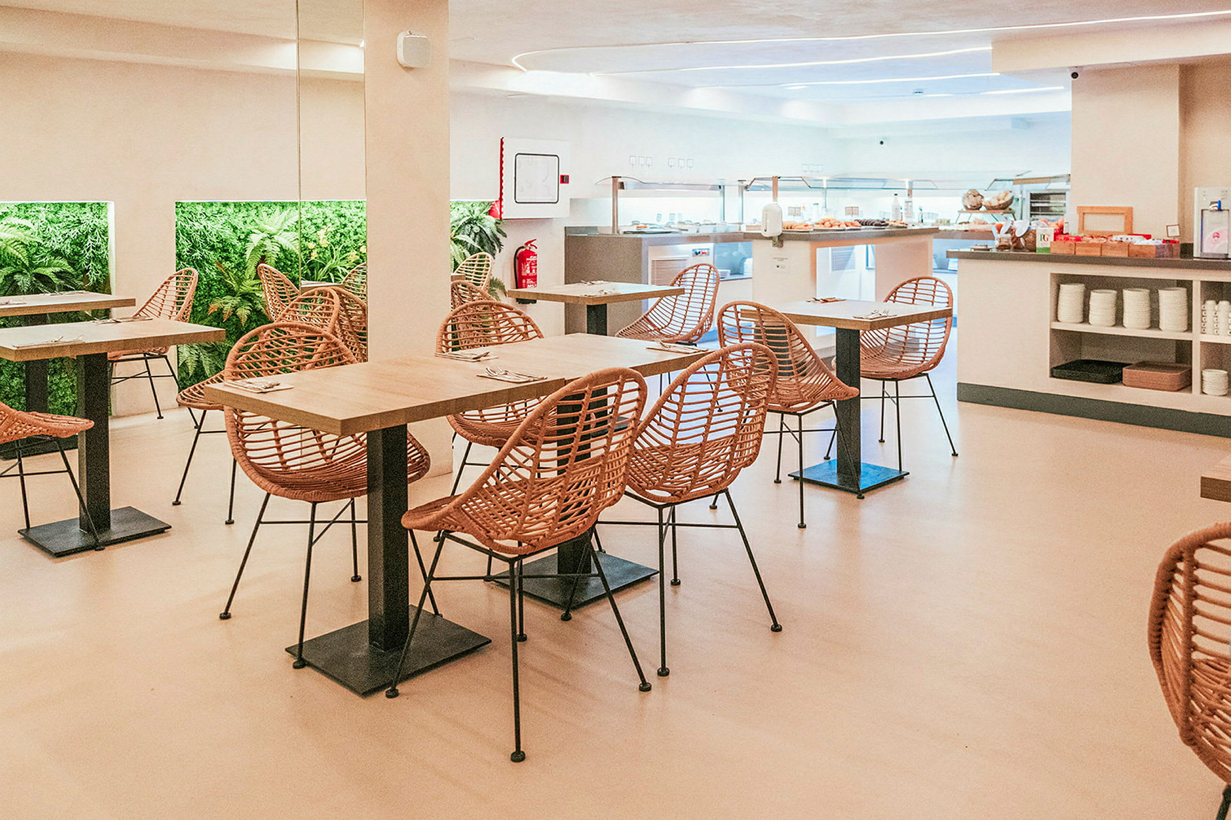 Kuva ruokasalista, jossa on pöytiä, tuoleja ja kasveja seinällä. (Tekoälyn luoma teksti)
