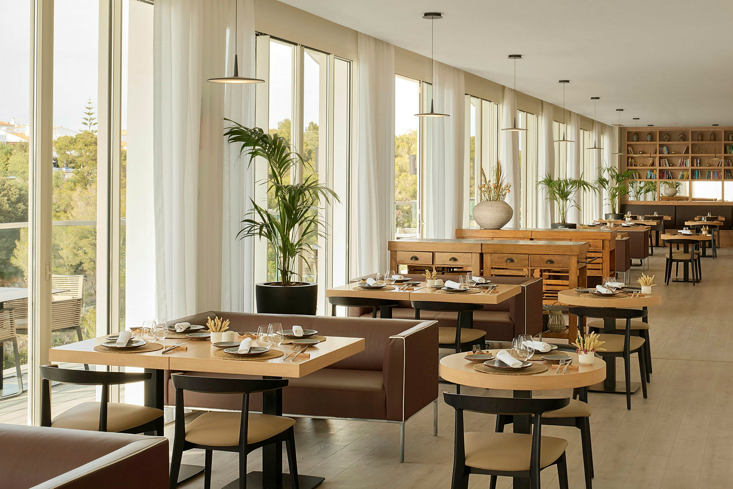 Valoisa ja tilava ravintola, jossa on suuret ikkunat, modernit kalusteet ja valmiiksi katetut pöydät. (Tekoälyn luoma teksti)
