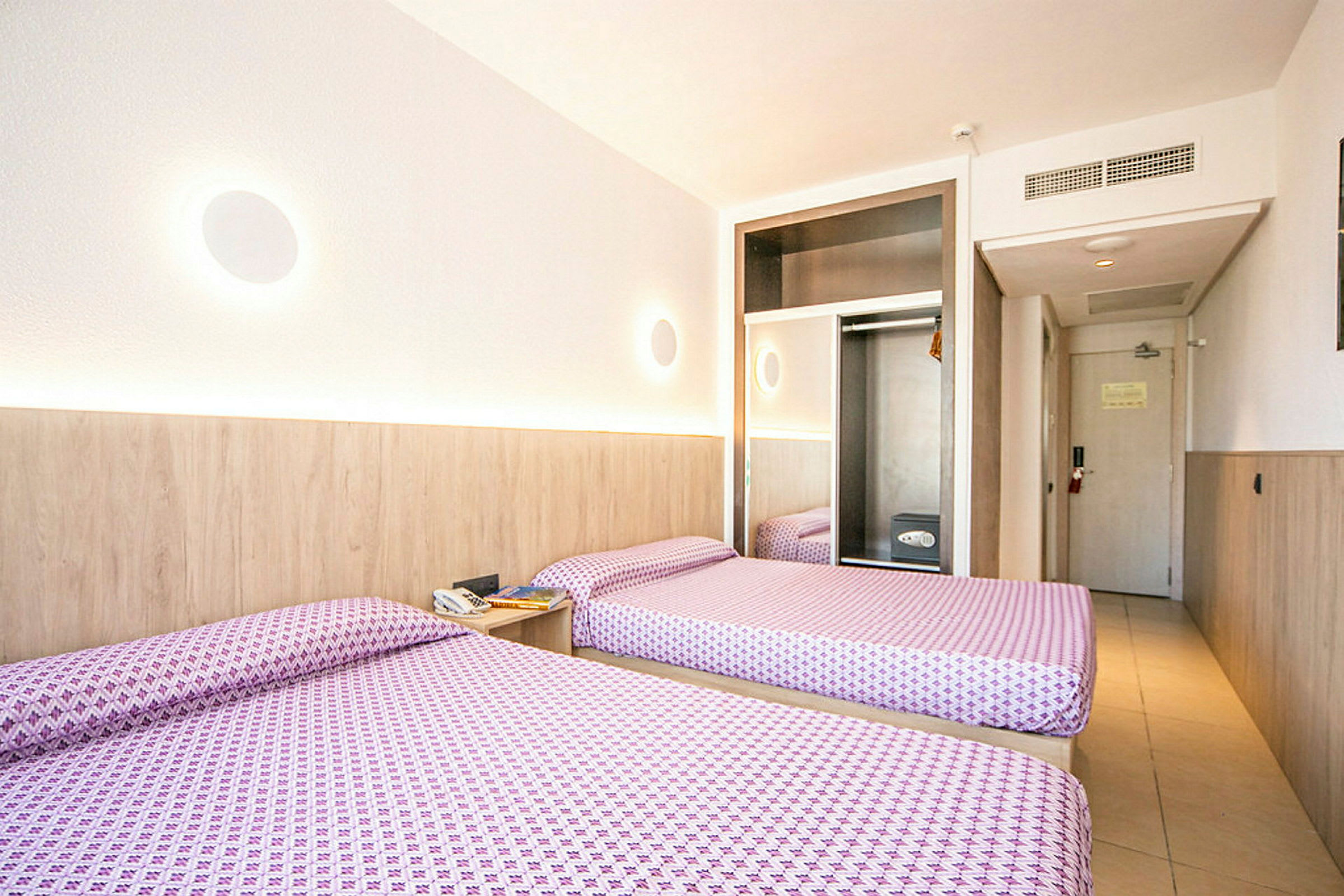 Hotellihuone, jossa kaksi yhden hengen sänkyä, vaatekaappi ja ovi. (Tekoälyn luoma teksti)