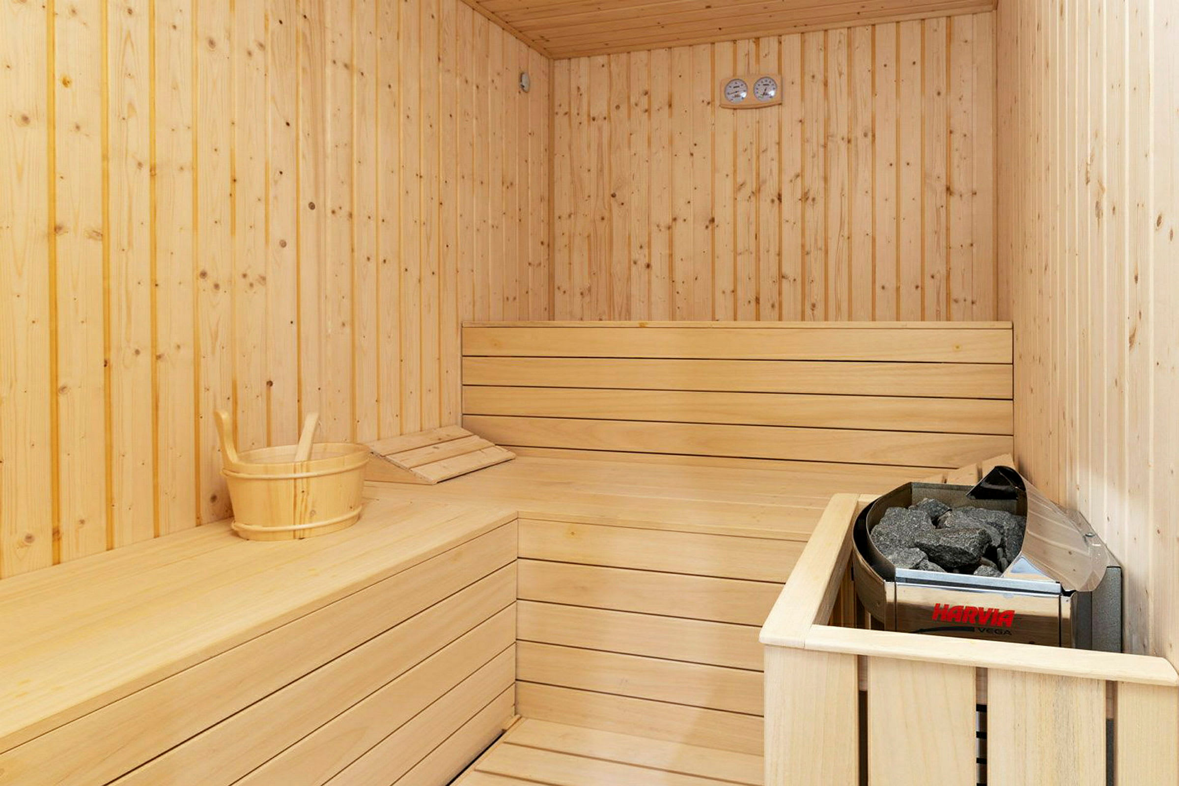 Sauna, jossa puupaneelit, saunanlauteet ja ämpäri kiukaan vieressä. (Tekoälyn luoma teksti)