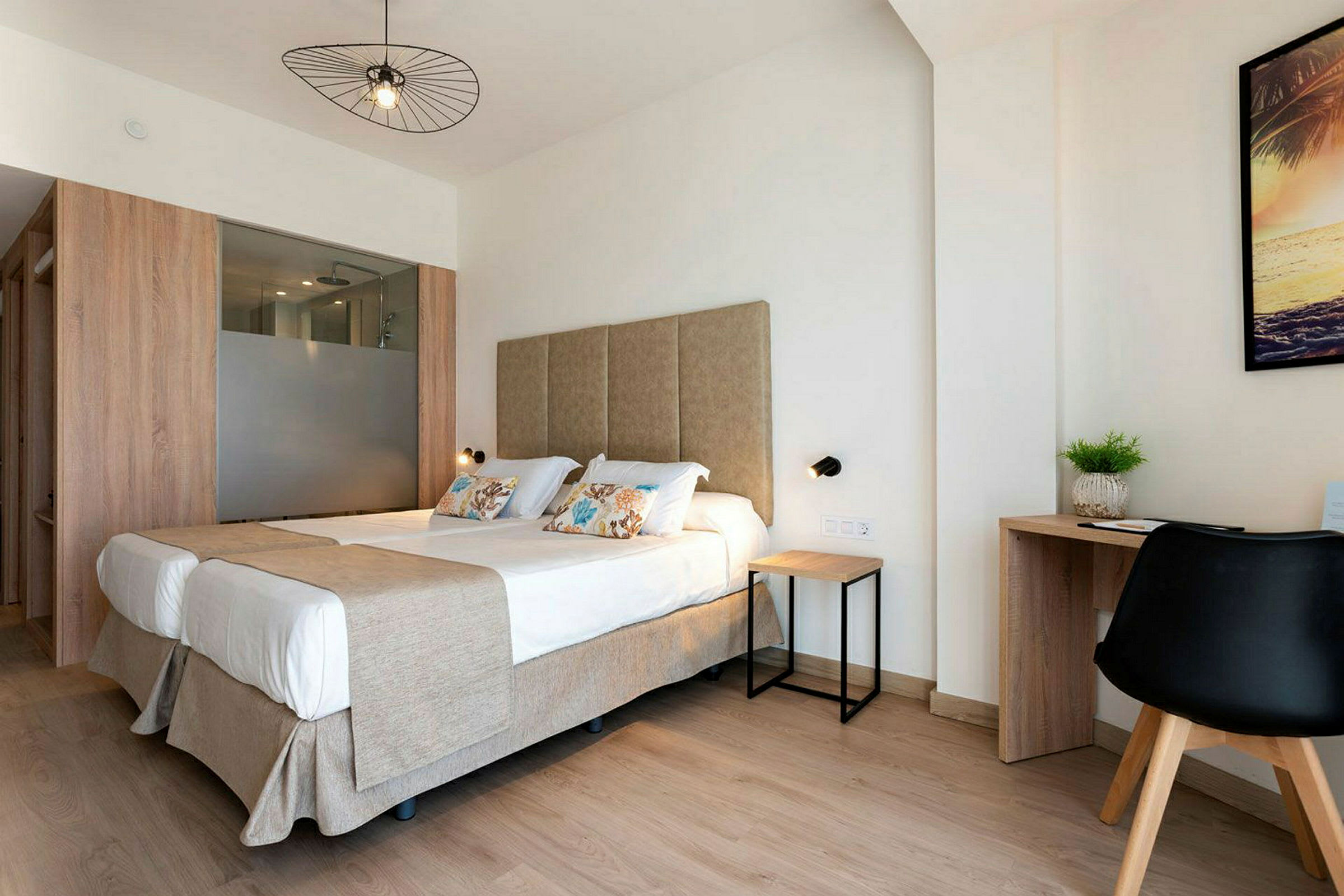 Valoisa hotellihuone, jossa on parivuode ja työpöytä. (Tekoälyn luoma teksti)