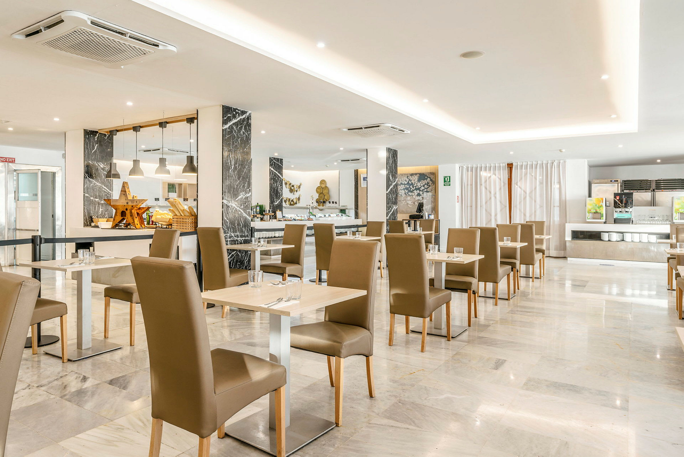 Moderni ravintola, jossa on valoisa ja avoin sisustus, pöytiä ja tuoleja pehmeissä väreissä sekä buffet taustalla. (Tekoälyn luoma teksti)