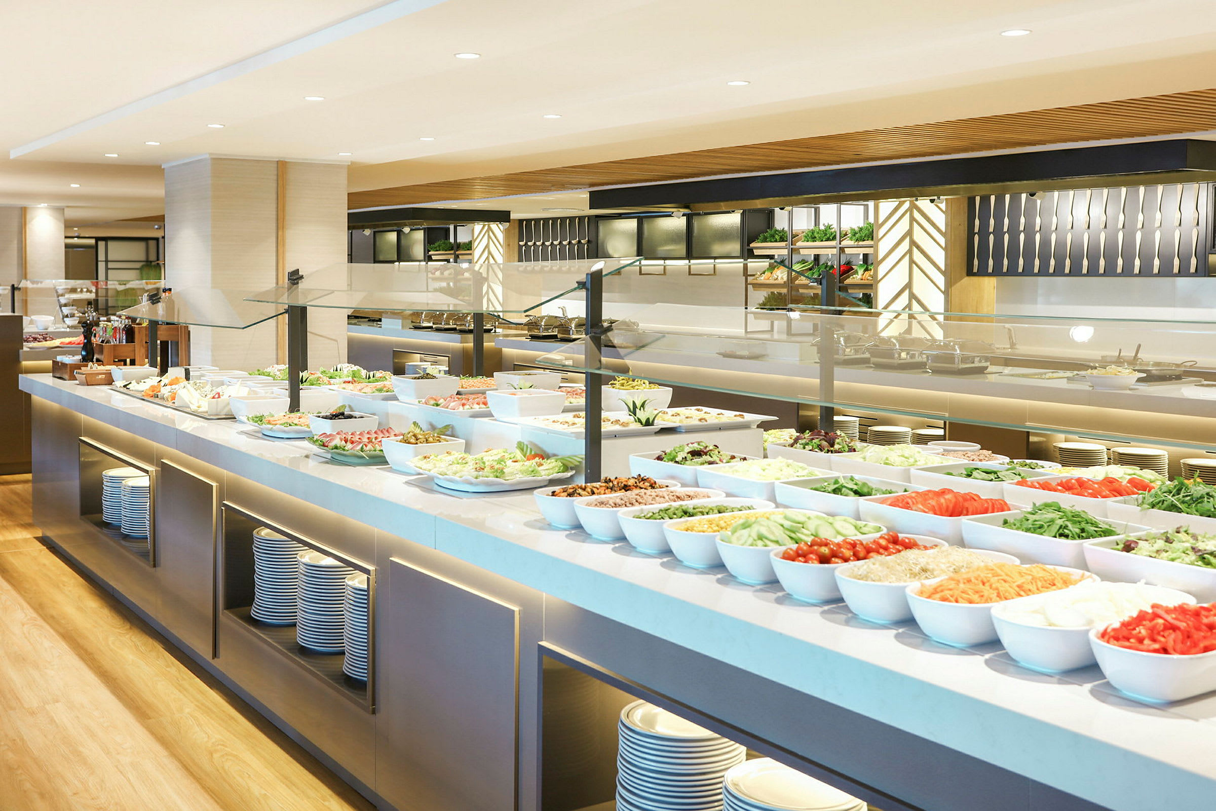 Buffet-alue, jossa erilaisia salaatteja ja lisukkeita valkoisissa tarjoiluastioissa. (Tekoälyn luoma teksti)