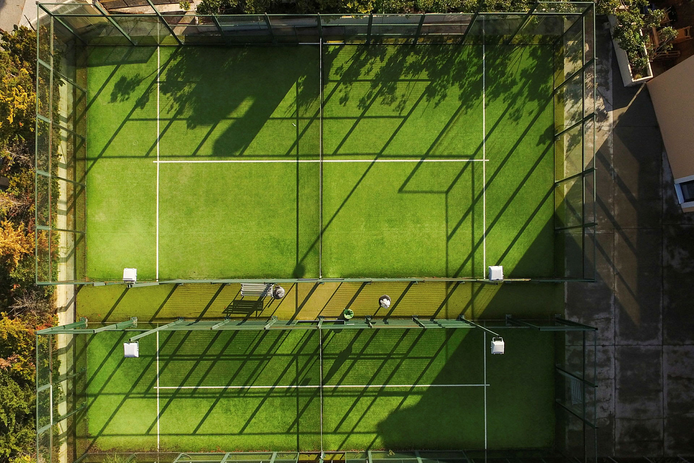 Ilmakuva aidatusta padelkentästä vihreällä tekonurmipinnoitteella. (Tekoälyn luoma teksti)