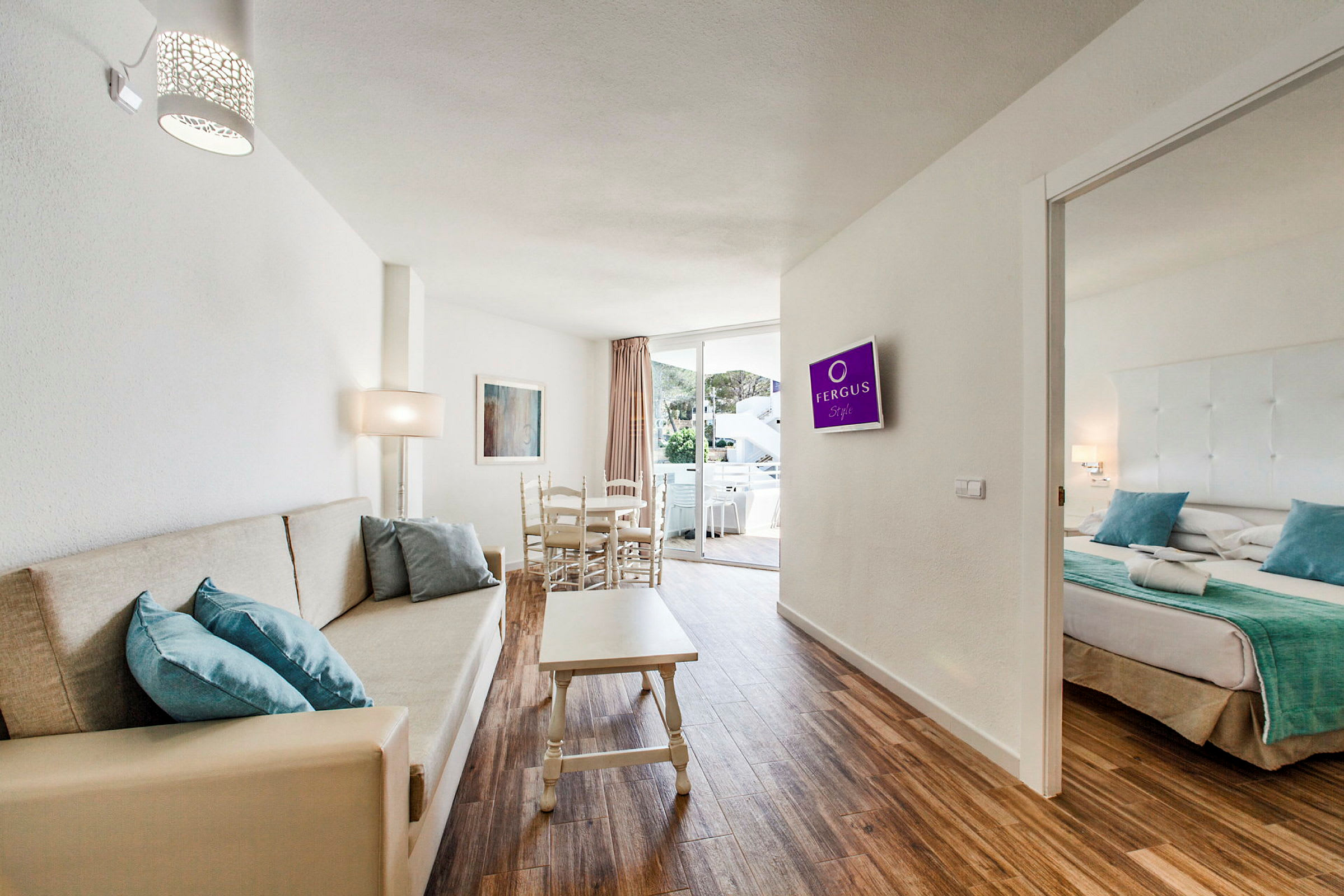Hotellihuoneen kuva, jossa on olohuone, sohva, ruokapöytä ja viereinen makuuhuone. (Tekoälyn luoma teksti)
