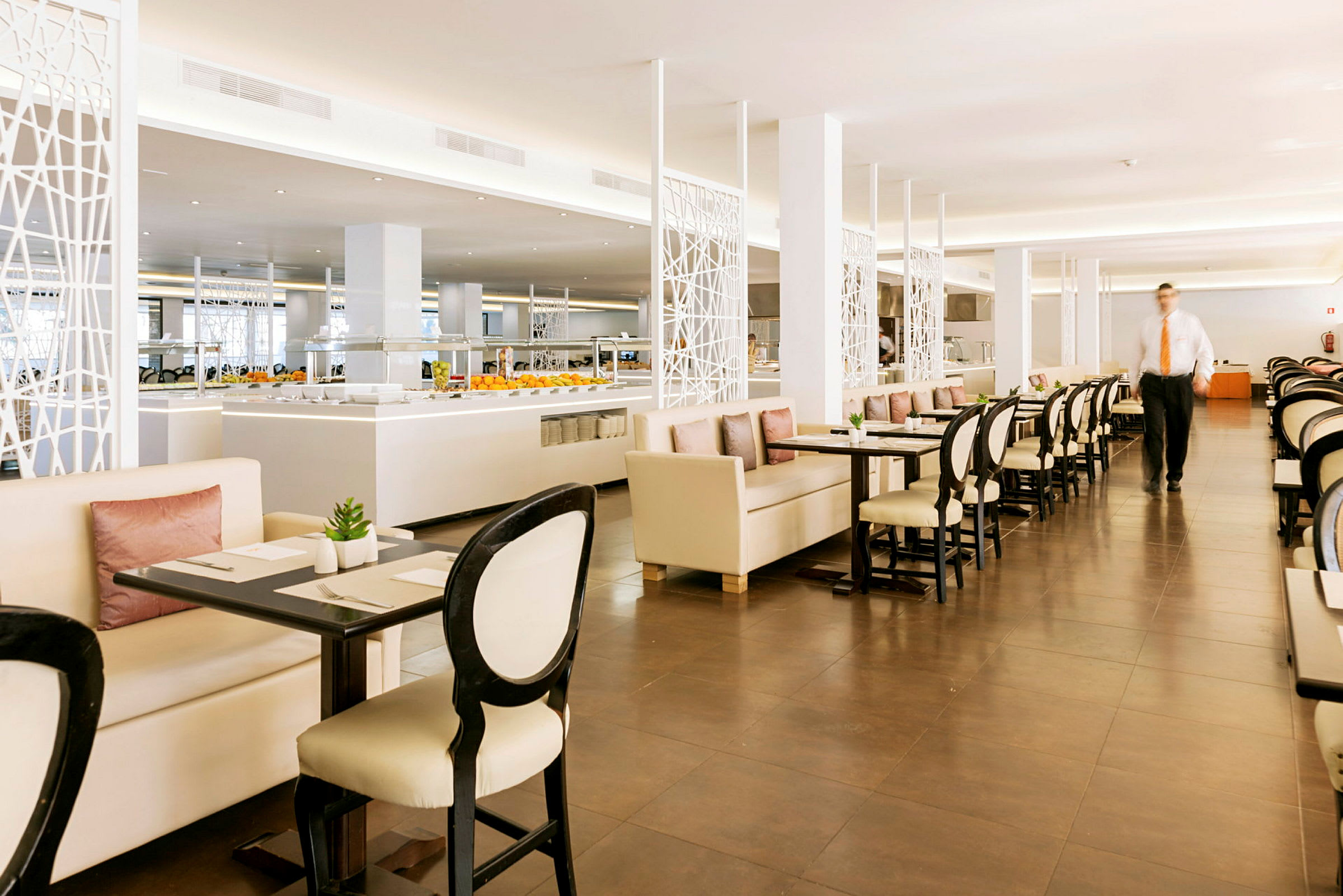 Ravintola, jossa on pöytiä ja tuoleja sekä buffet tarjoilualue taustalla. (Tekoälyn luoma teksti)
