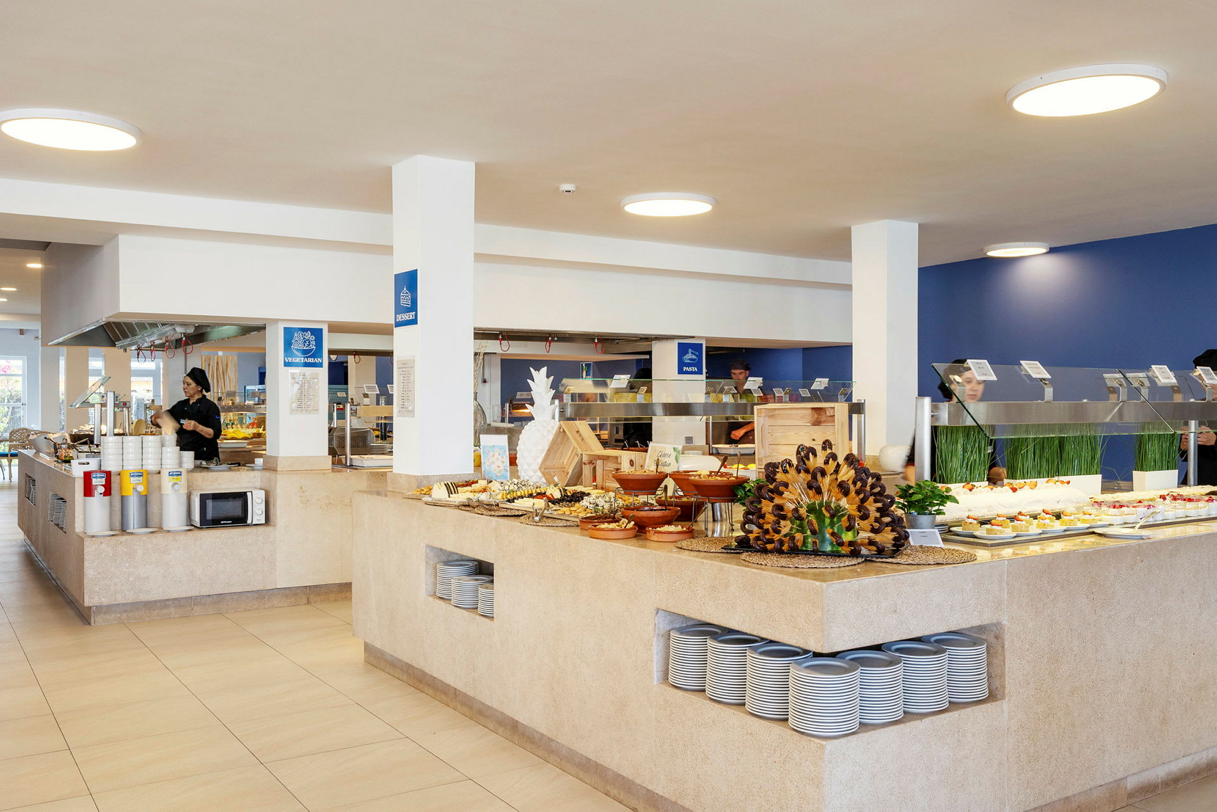 Buffet-alue modernissa ruokailutilassa, jossa on erilaisia ruokia esillä pöydillä ja hyllyillä. (Tekoälyn luoma teksti)