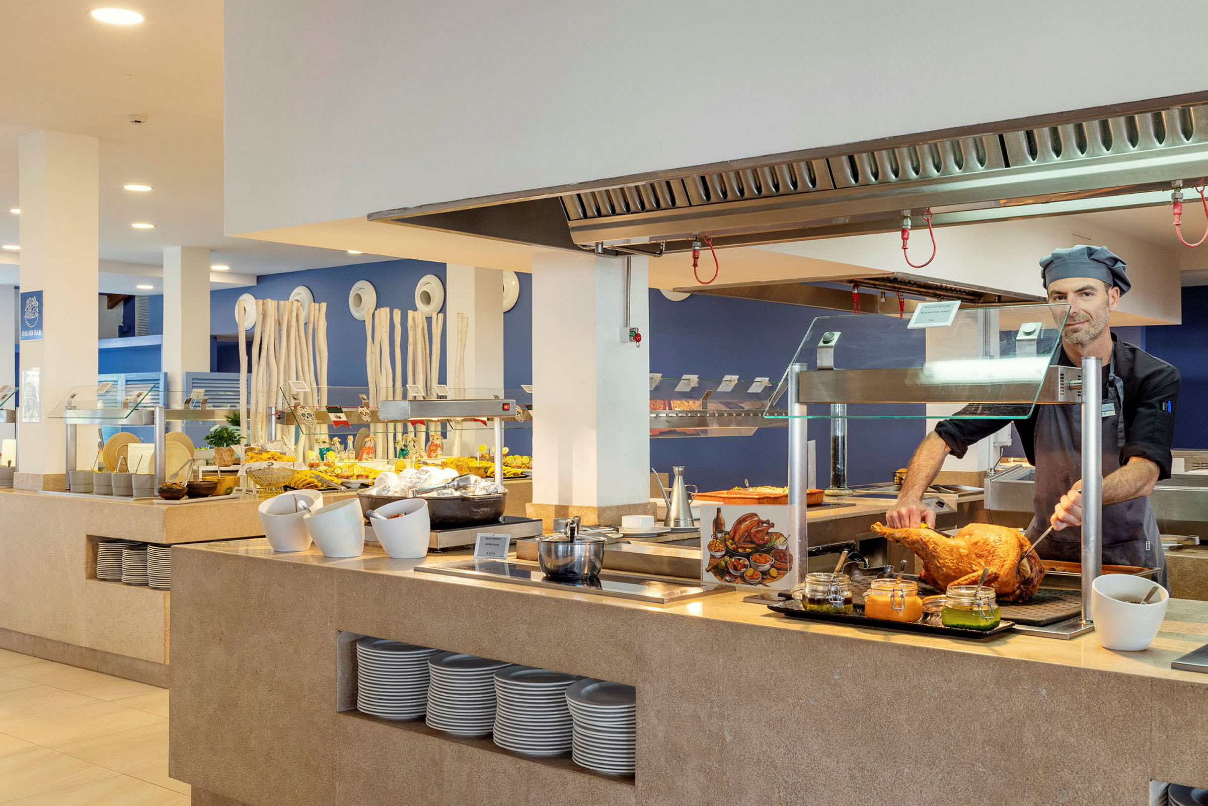Kokki leikkaa lihaa tiskin takana, taustalla salaattibuffet. (Tekoälyn luoma teksti)