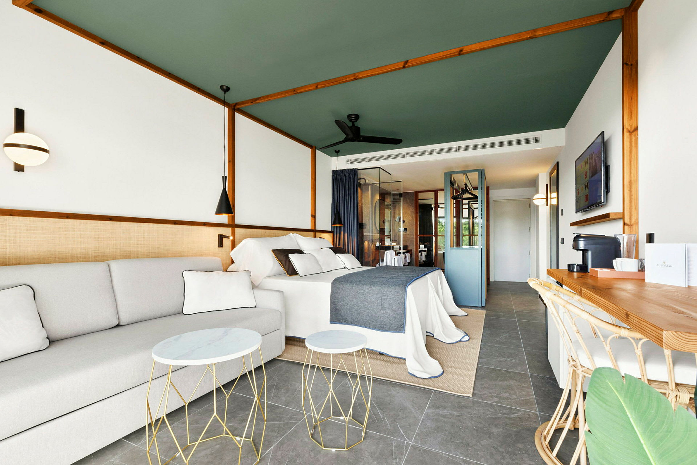 Moderni hotellihuone, jossa on sänky, sohva ja työtila. (Tekoälyn luoma teksti)