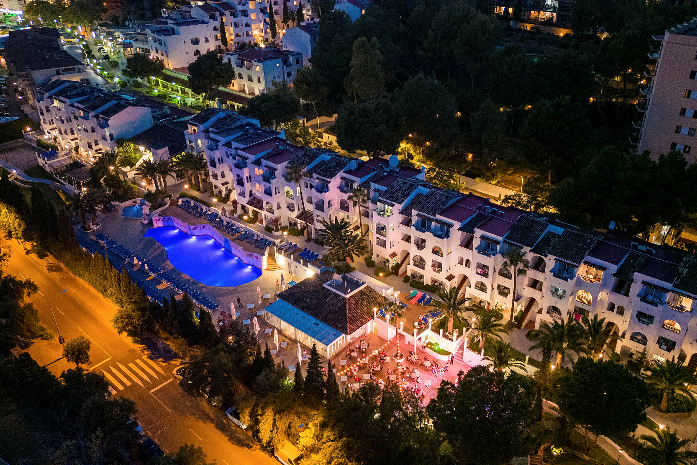 Ilmakuva valaistusta hotellialueesta, jossa on uima-allas ja terassi illalla. (Tekoälyn luoma teksti)