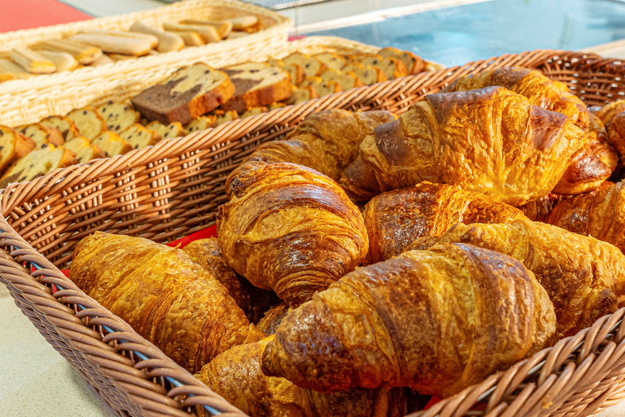 Kori, jossa croissanteja, taustalla erilaisia leivonnaisia. (Tekoälyn luoma teksti)