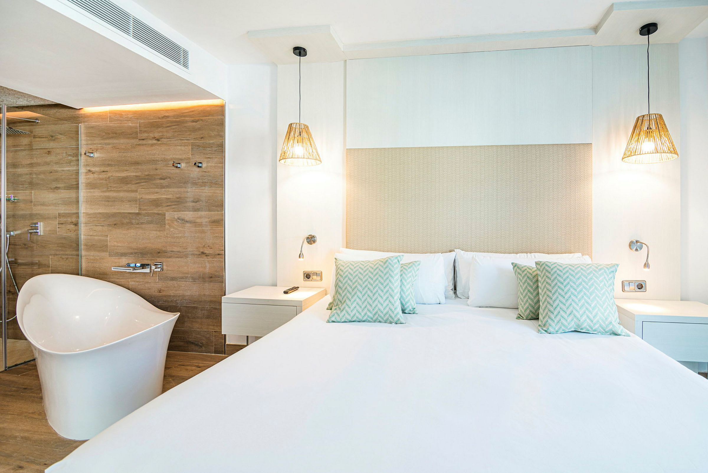 Moderni hotellihuone, jossa on suuri sänky, valkoiset seinät ja erillinen kylpyamme. (Tekoälyn luoma teksti)