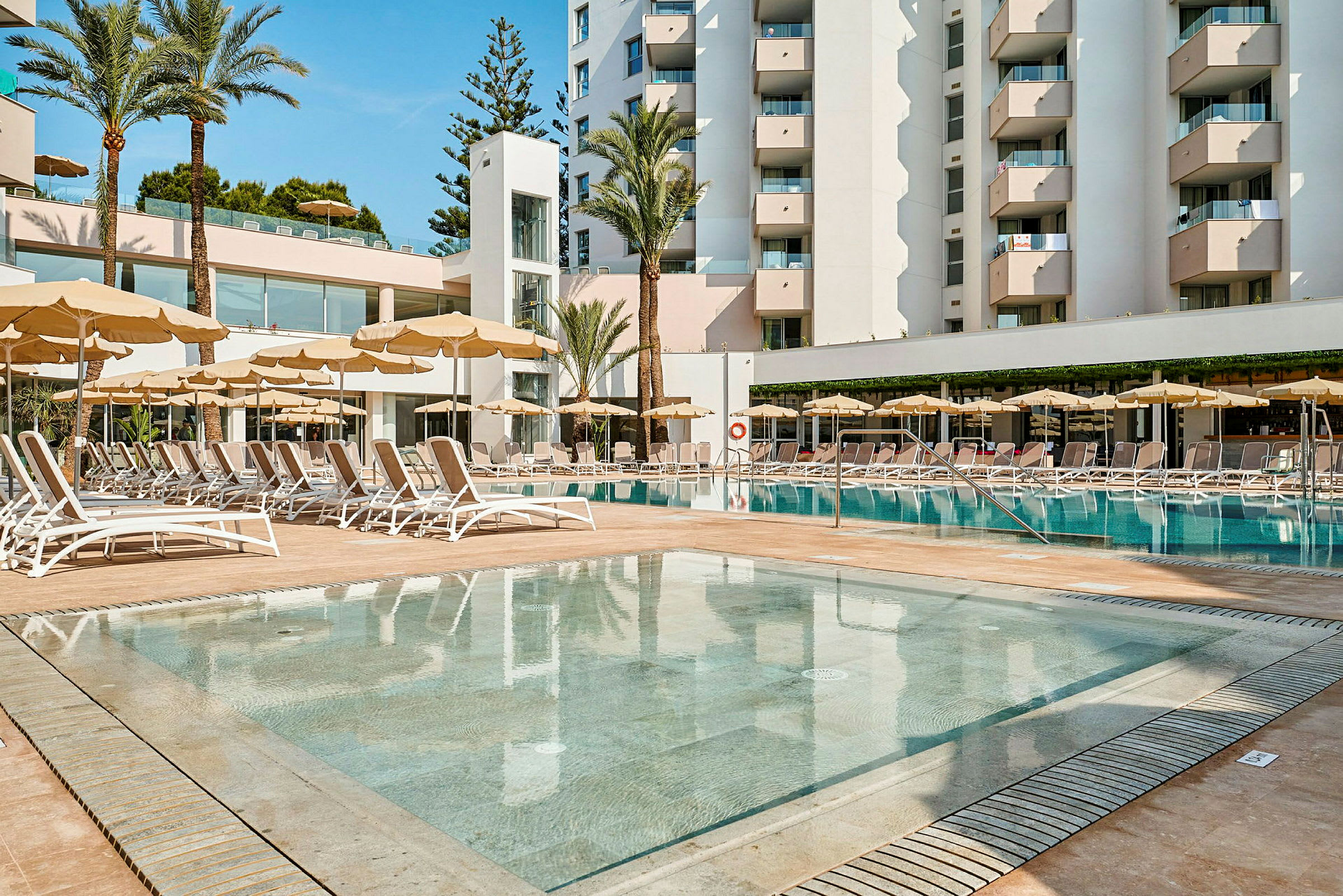 Hotellikompleksi, jossa on uima-allas ja aurinkotuoleja. (Tekoälyn luoma teksti)