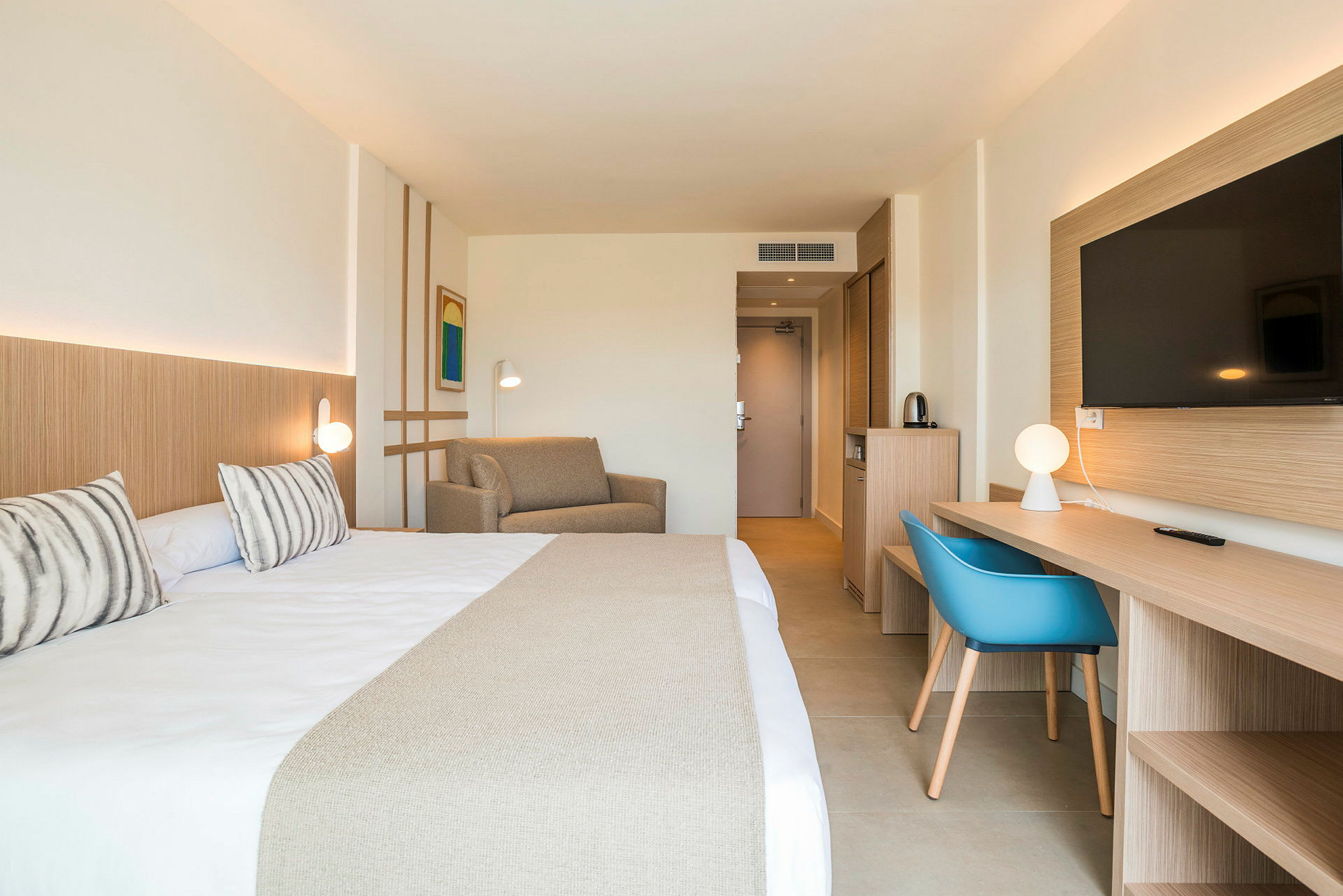 Hotellihuone, jossa on parisänky, sohva, työpöytä ja TV. (Tekoälyn luoma teksti)
