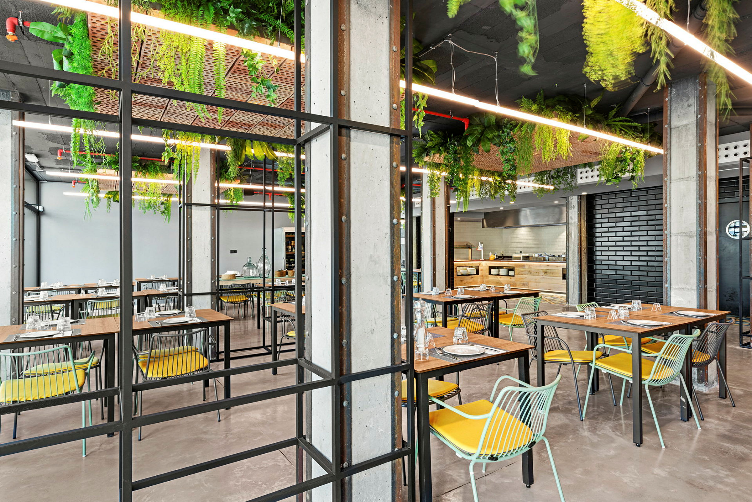 Moderni ravintola, jossa pöytiä, tuoleja ja katosta roikkuvia kasveja. (Tekoälyn luoma teksti)