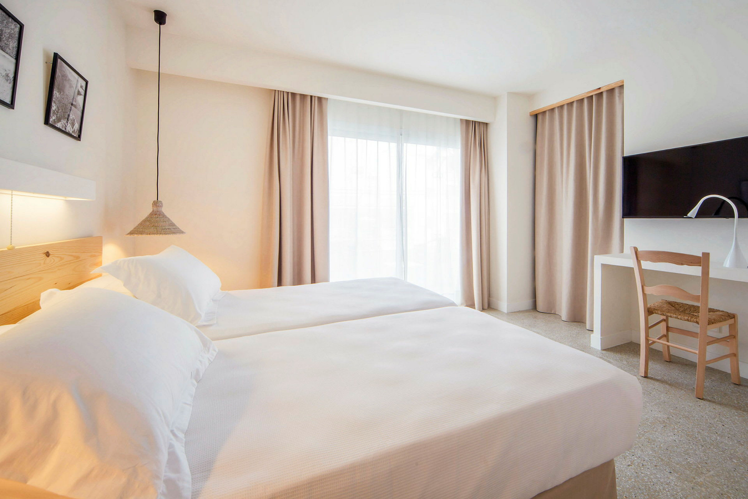 Moderni hotellihuone, jossa kaksi yhden hengen sänkyä, kirjoituspöytä ja televisio. (Tekoälyn luoma teksti)