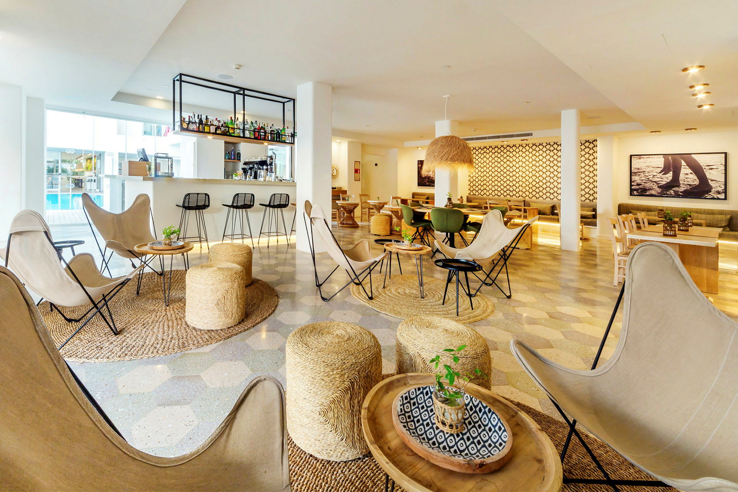Modernisti sisustettu lounge-alue, jossa pöytiä, tuoleja ja istuimia, sekä baari taustalla. (Tekoälyn luoma teksti)