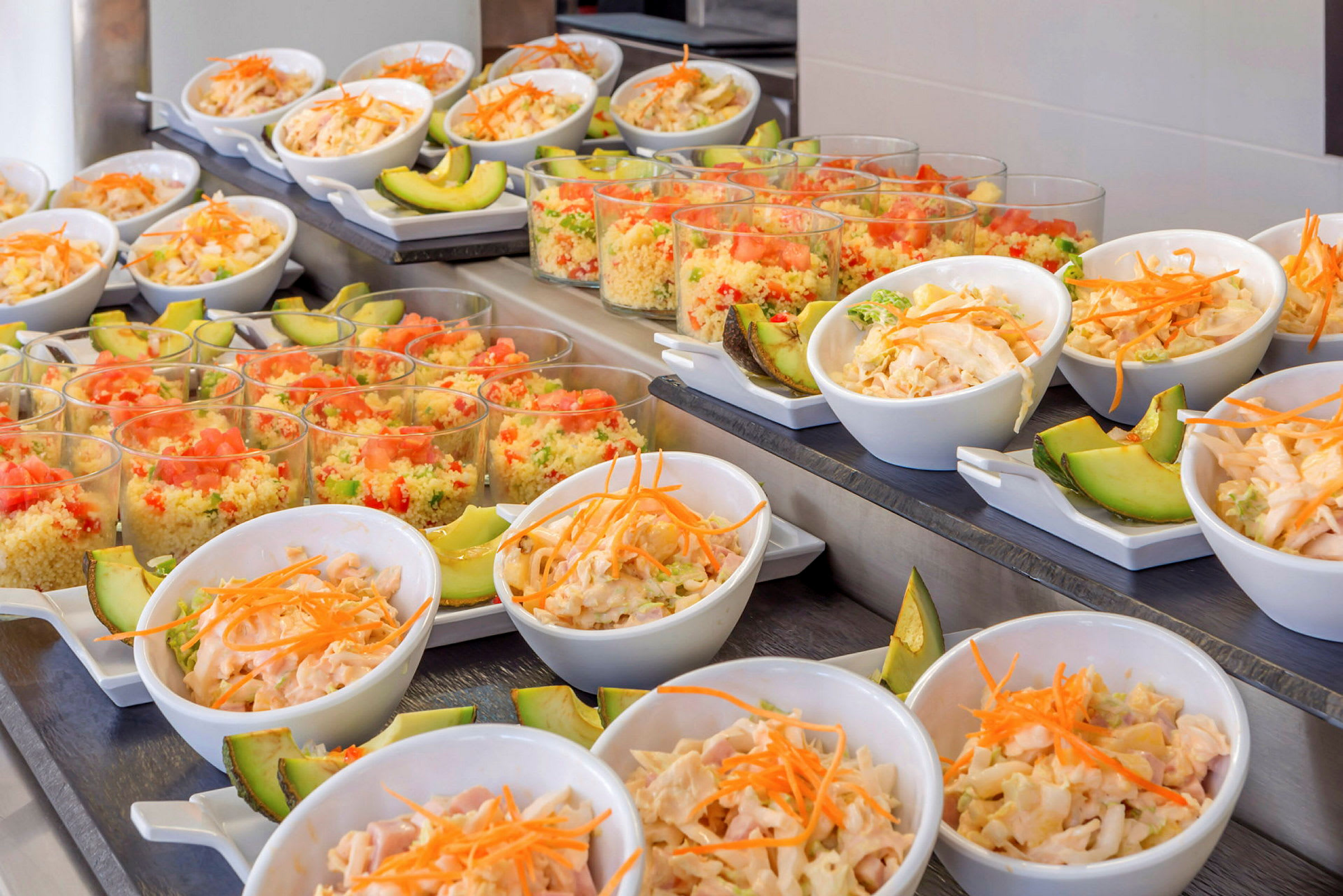 Buffet, jossa pieniä kulhoja salaattia ja avokadoa sekä värikkäitä couscousannoksia sisältäviä laseja. (Tekoälyn luoma teksti)