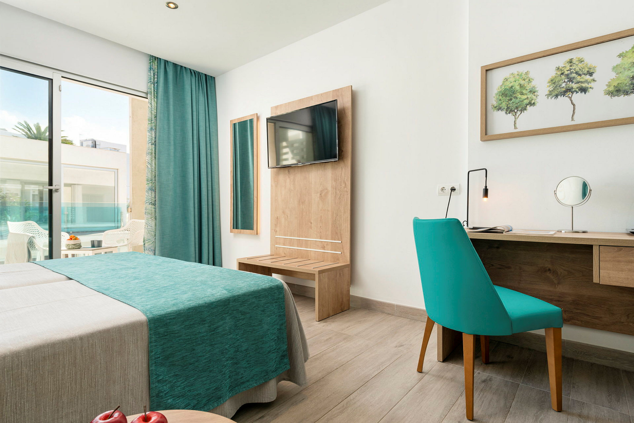 Hotellihuone, jossa sininen sohva, peili, kirjoituspöytä ja pääsy parvekkeelle. (Tekoälyn luoma teksti)