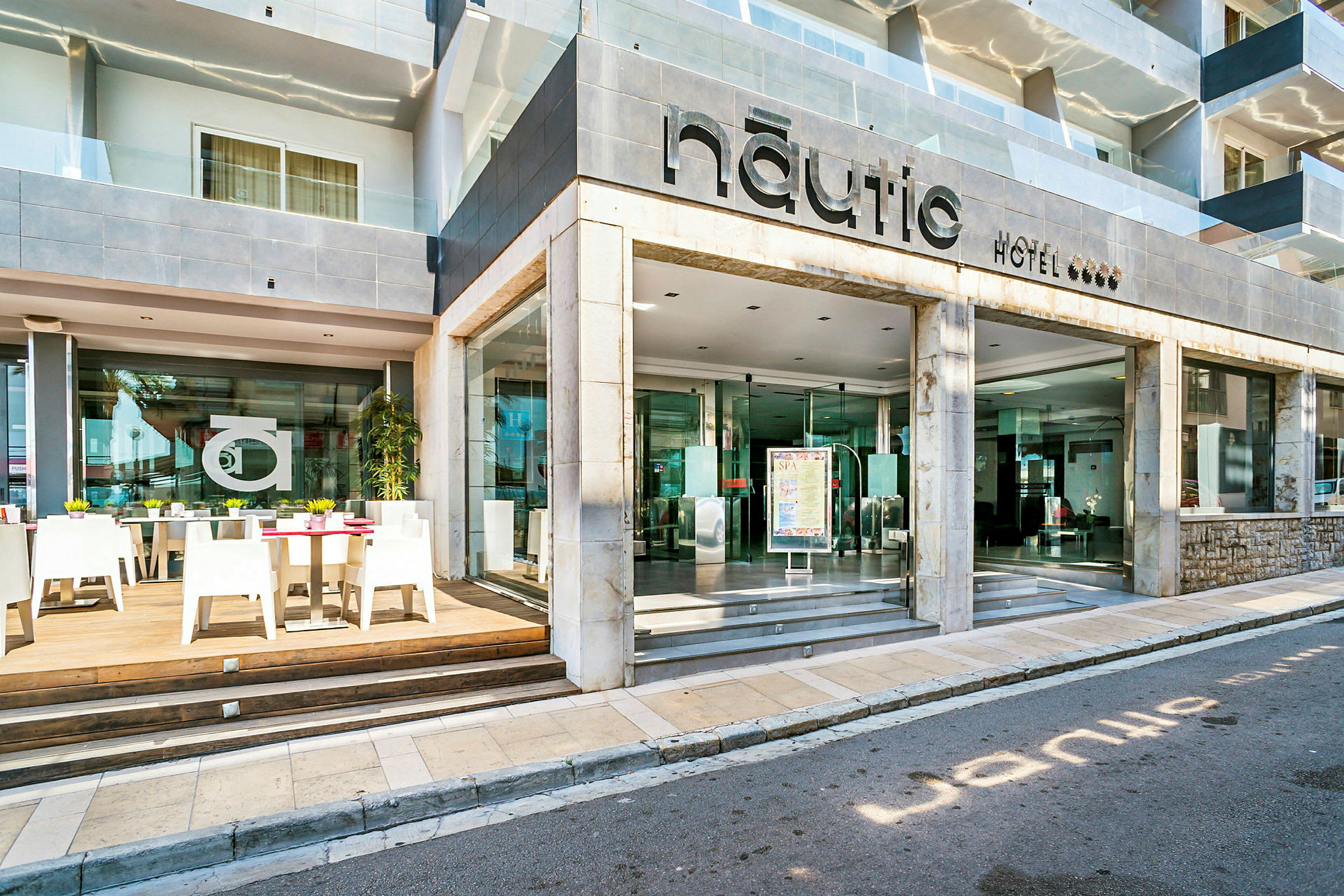 Hotel Nauticin sisäänkäynti ja ulkoterassi pöytineen ja tuoleineen. (Tekoälyn luoma teksti)