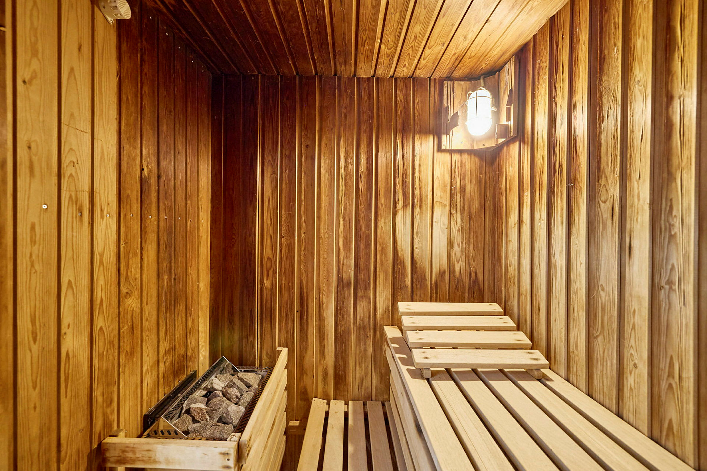 Puiset seinät sisältävä sauna, jossa on puurakenteiset istuimet ja kivikiuas. (Tekoälyn luoma teksti)
